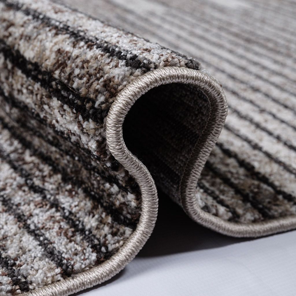 Tapis enroulé avec une texture touffue et des rayures horizontales abstraites marron, beiges et noires, bordure cousue