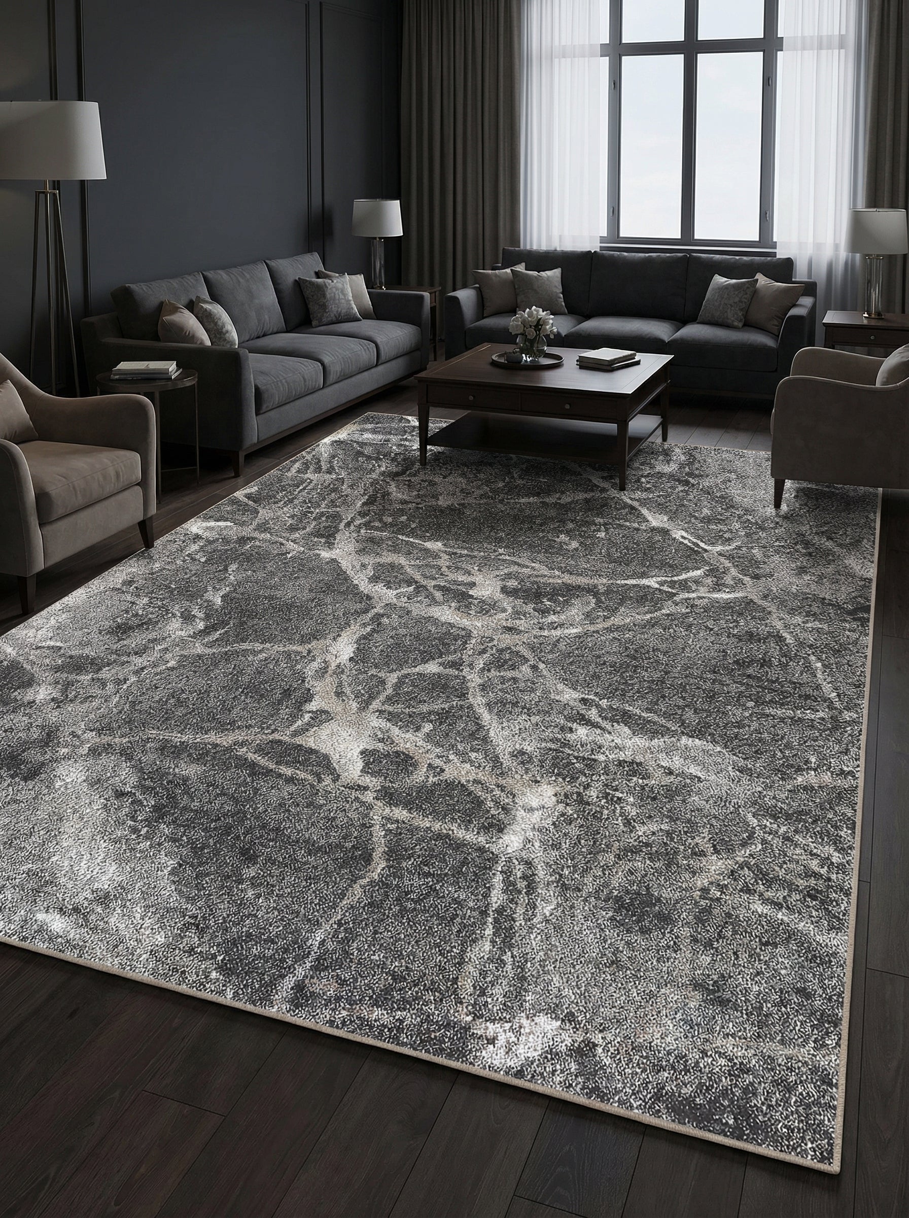 Tapis rectangulaire gris foncé à motifs marbrés clairs et abstraits, posé sur un sol en bois sombre dans un salon élégant
