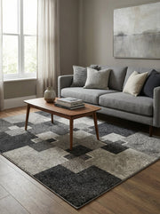 Tapis moelleux rectangulaire à motifs de blocs géométriques gris foncé, gris moyen et gris clair, posé sur un parquet dans un salon