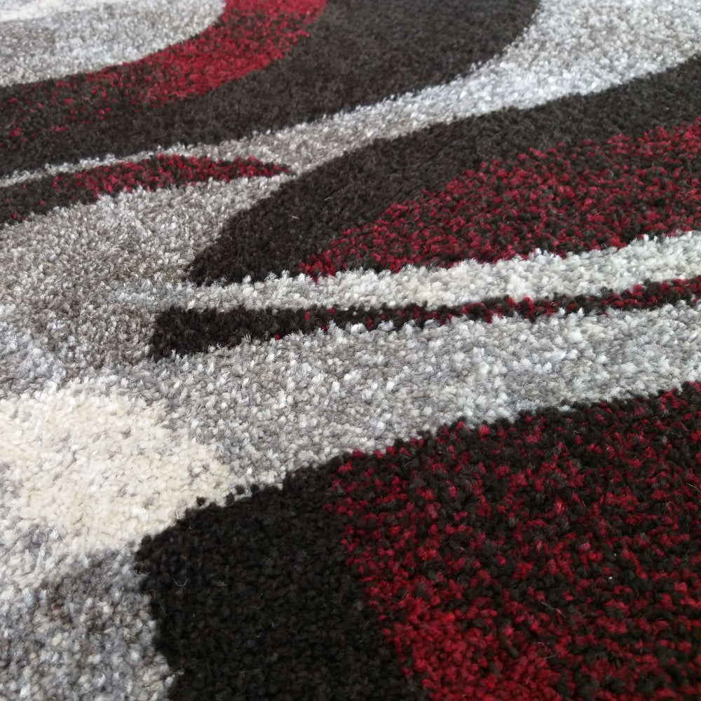 Un tapis à motifs abstraits avec des vagues de couleurs rouge, noir, gris et blanc, à la texture moelleuse