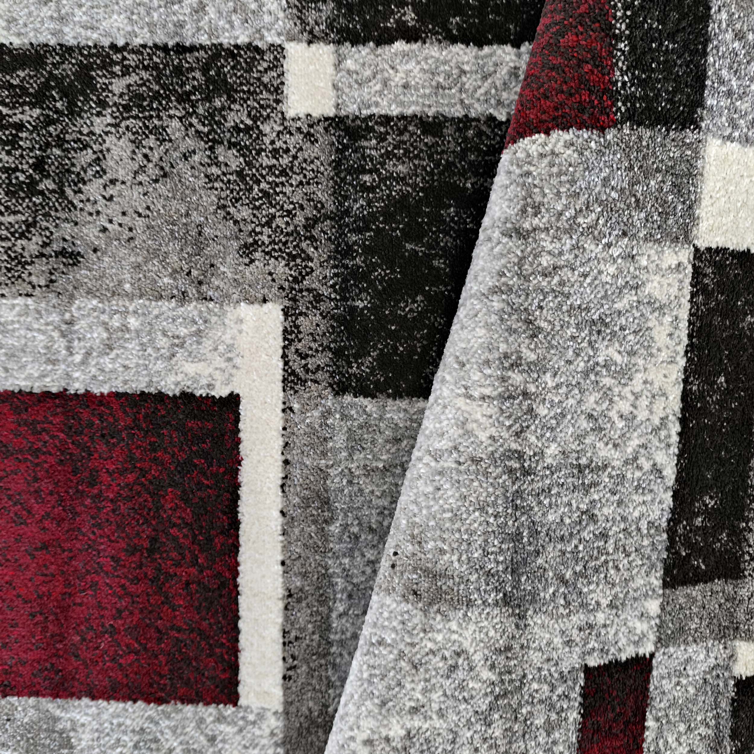 Tapis à motif géométrique abstrait de blocs gris, noirs, blancs et rouge foncé, avec une texture bouclée