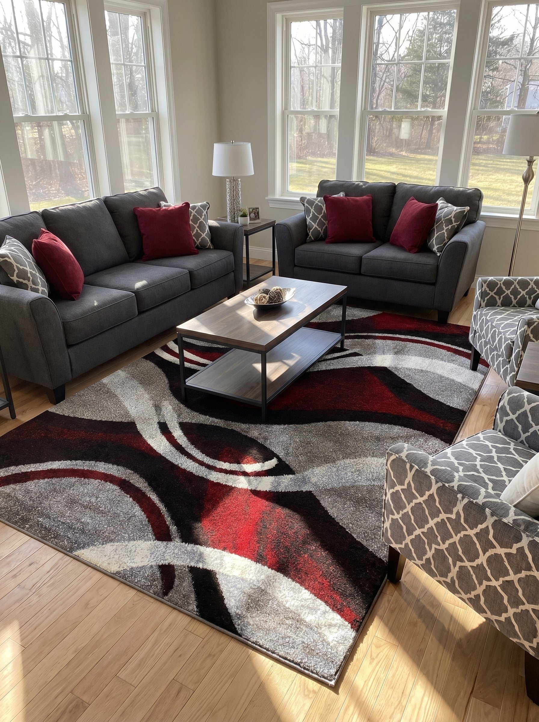 Tapis rectangulaire aux motifs abstraits ondulants rouge, gris, noir et blanc, posé sur un parquet clair dans un salon