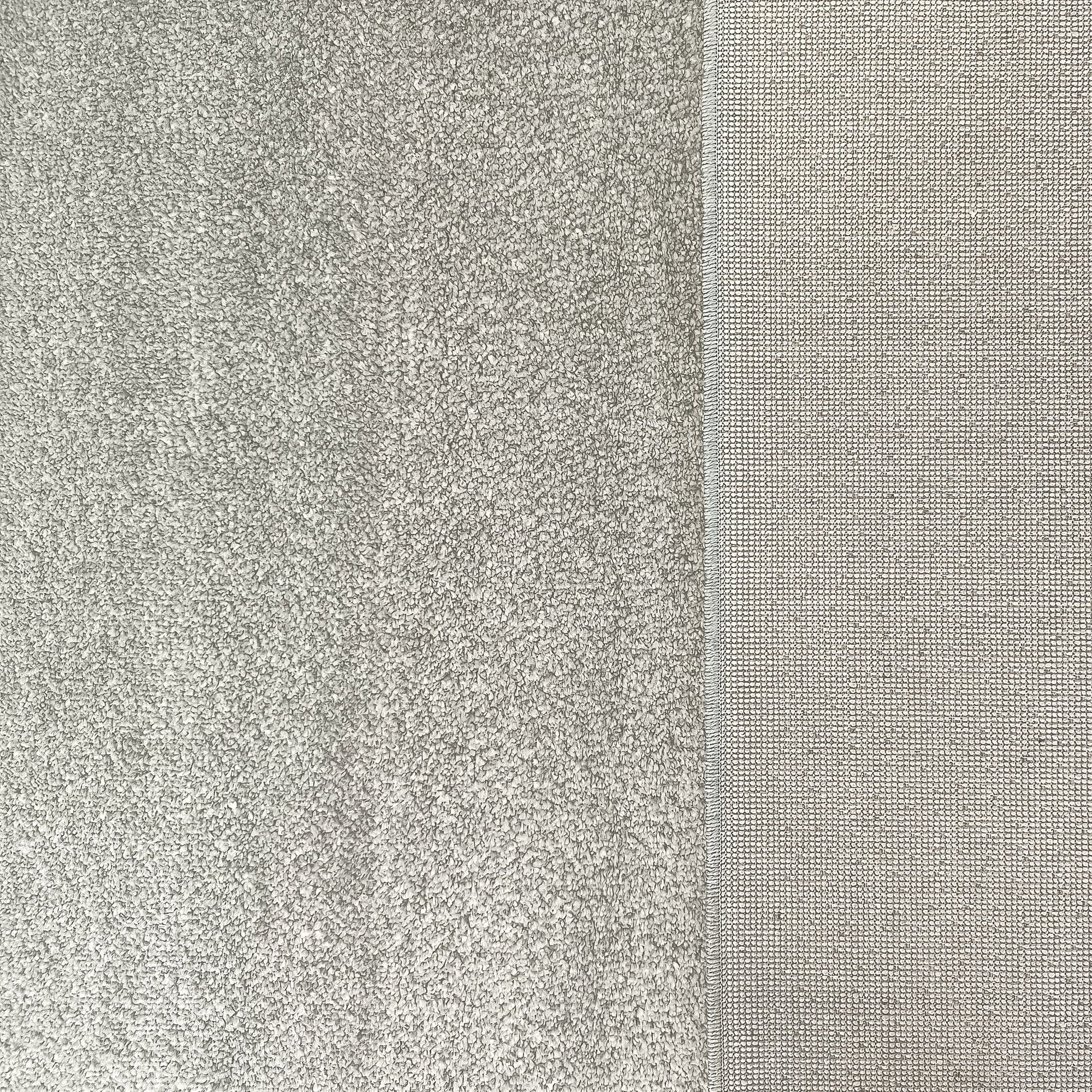 Tapis gris clair montrant deux textures distinctes : une partie touffue à longs poils et une section à tissage fin régulier