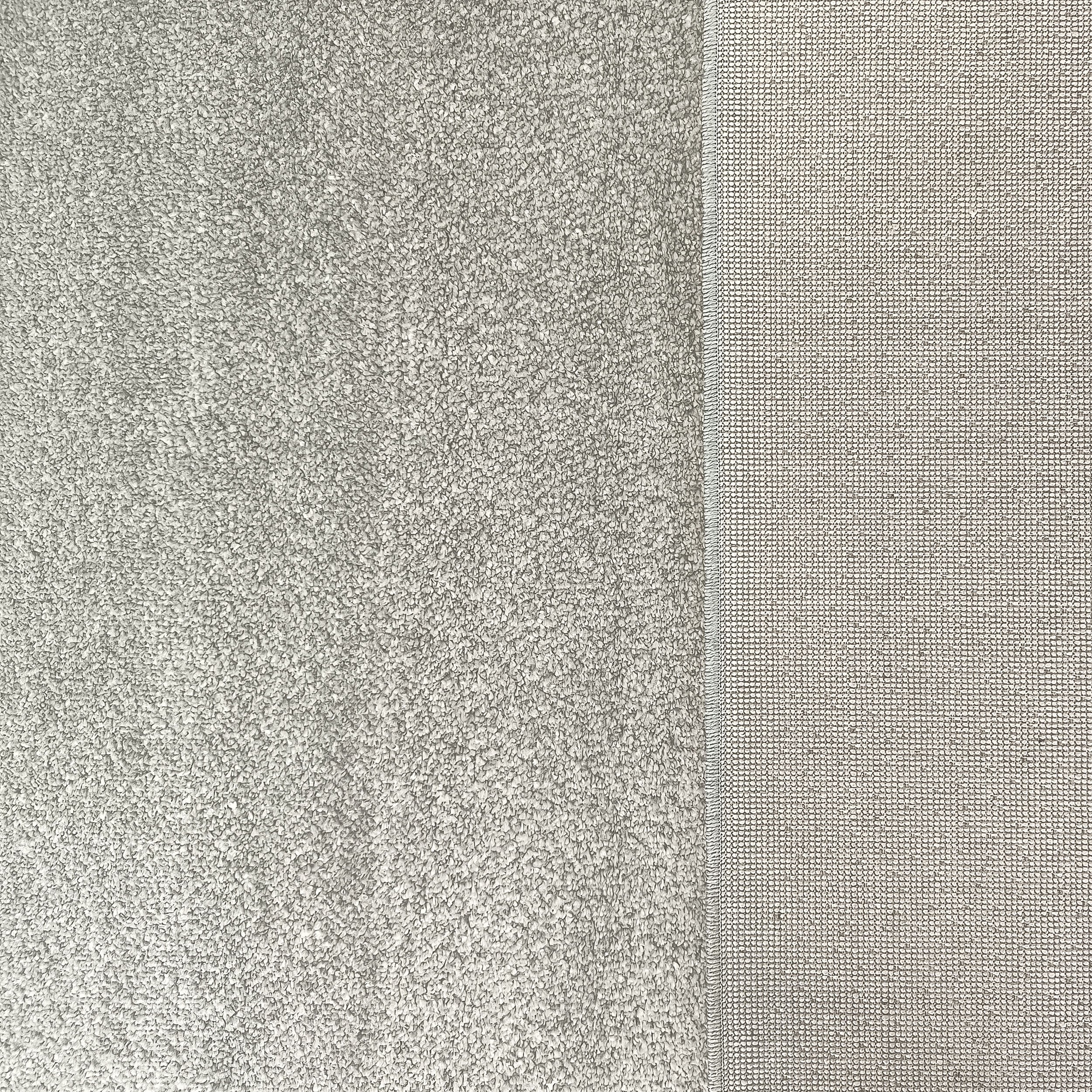 Tapis gris clair montrant deux textures distinctes : une partie touffue à longs poils et une section à tissage fin régulier