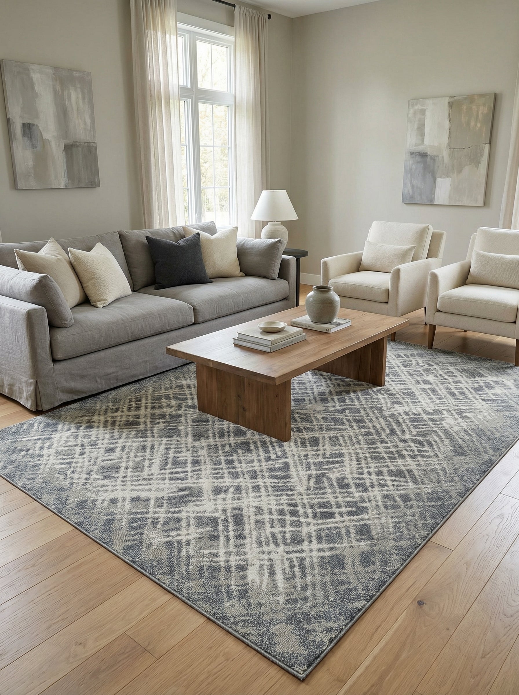 Tapis rectangulaire gris et blanc cassé avec un motif abstrait tissé de lignes irrégulières, posé sur un parquet clair dans un salon