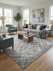 Tapis rectangulaire bleu-gris et crème, à motif géométrique abstrait texturé, dans un salon moderne