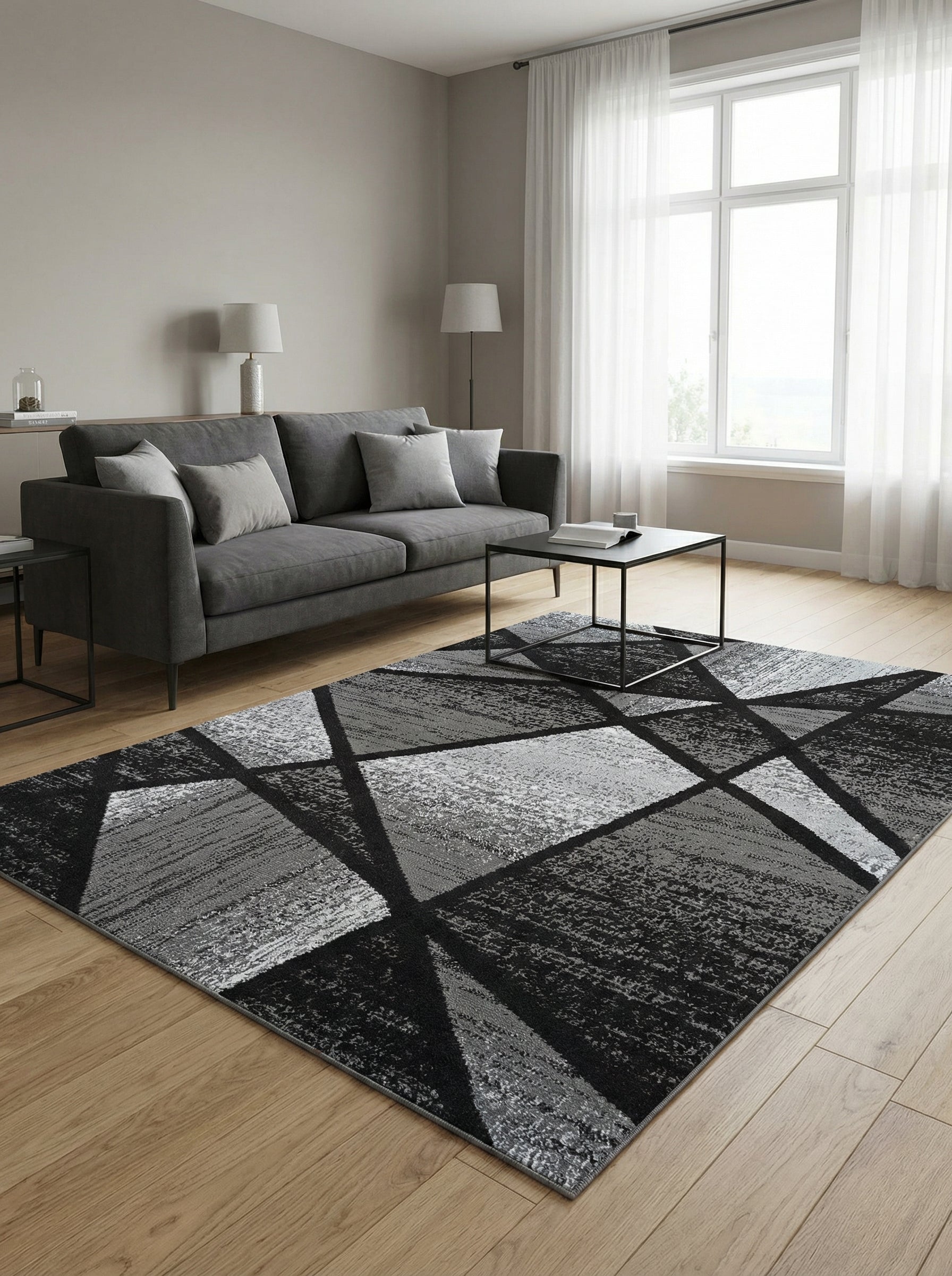 Tapis rectangulaire gris et noir aux motifs géométriques abstraits et texturés posé sur un parquet clair dans un salon moderne