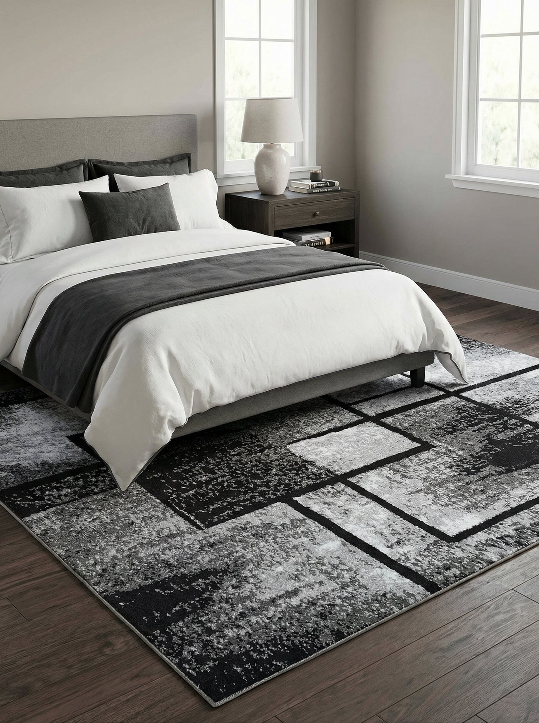 Tapis rectangulaire aux motifs géométriques abstraits noir, gris et blanc, avec une texture mouchetée, dans une chambre