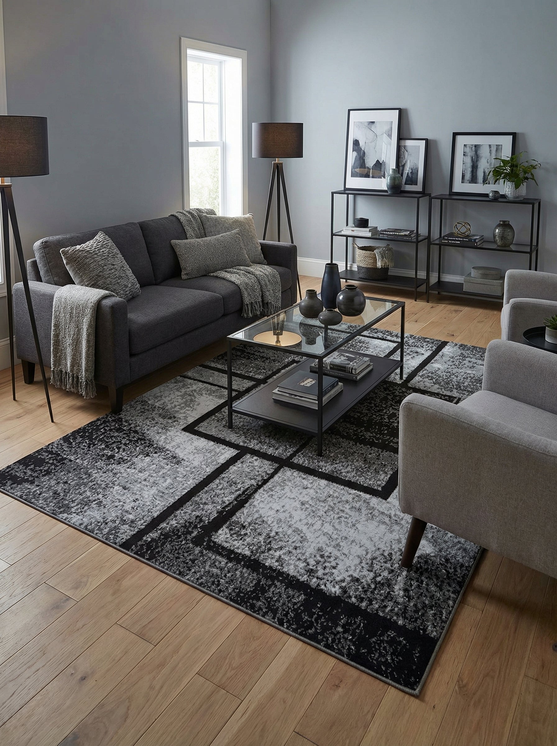 Tapis rectangulaire abstrait noir et gris avec des motifs géométriques et un aspect moucheté, posé sur un parquet dans un salon