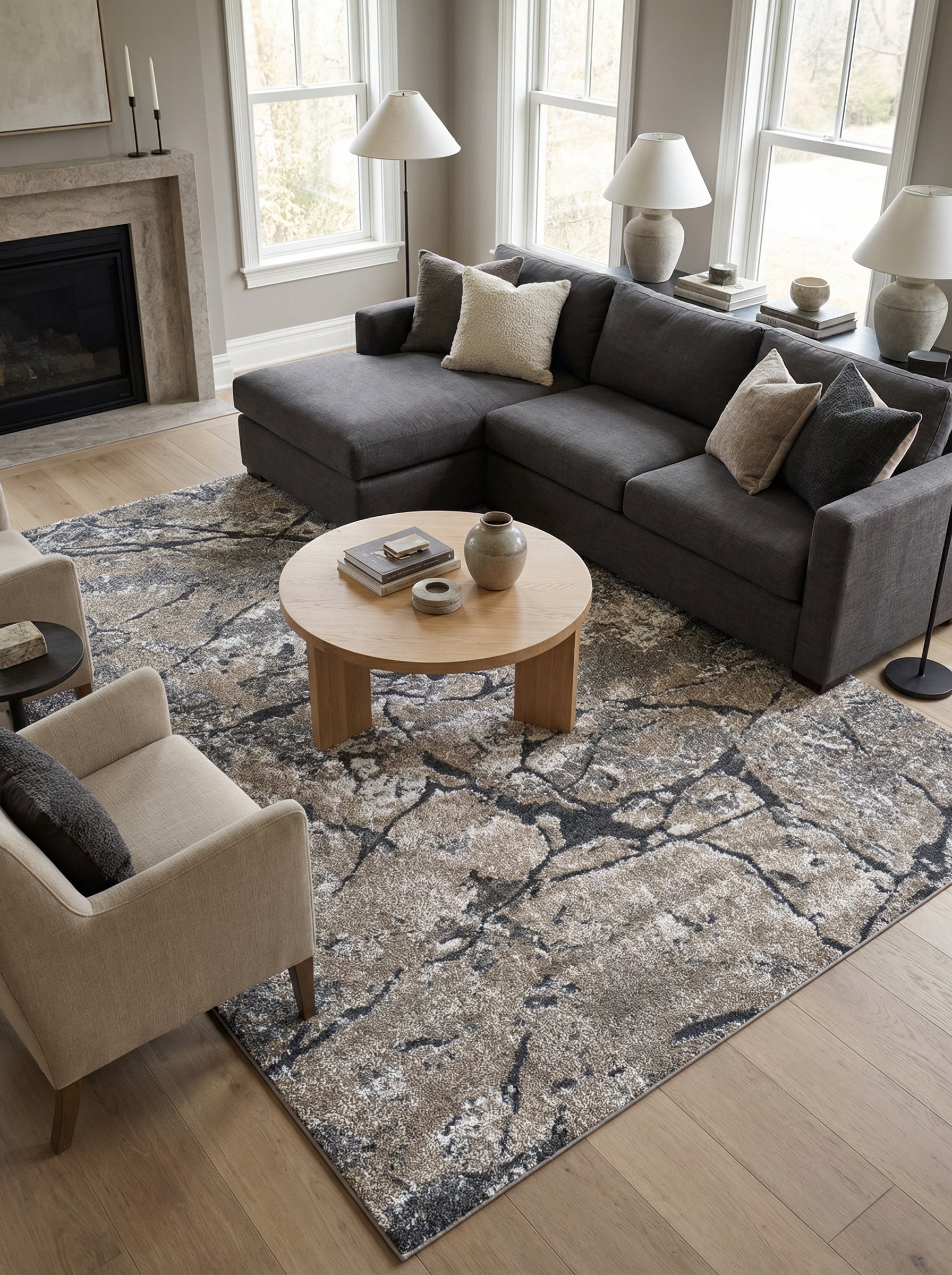 Tapis rectangulaire aux motifs abstraits marbrés en beige, marron, gris et blanc, posé sur un plancher en bois dans un salon