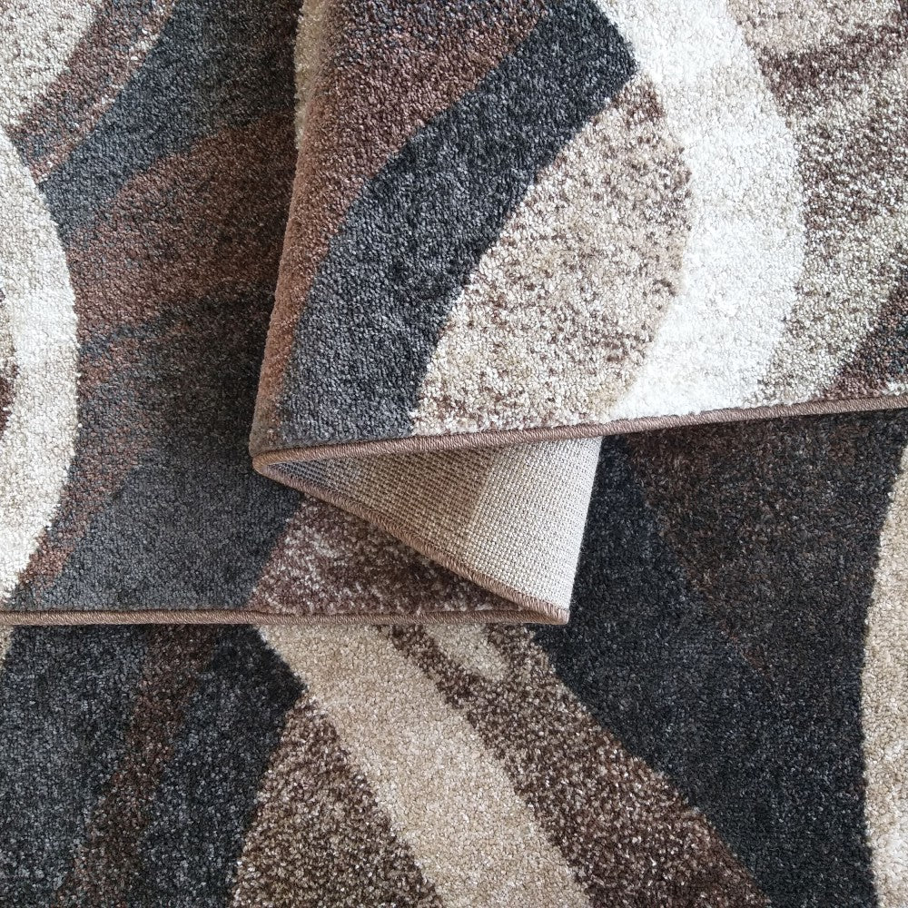 Tapis à poils coupés aux motifs abstraits et ondulés en teintes de marron, beige, gris et blanc, un coin plié