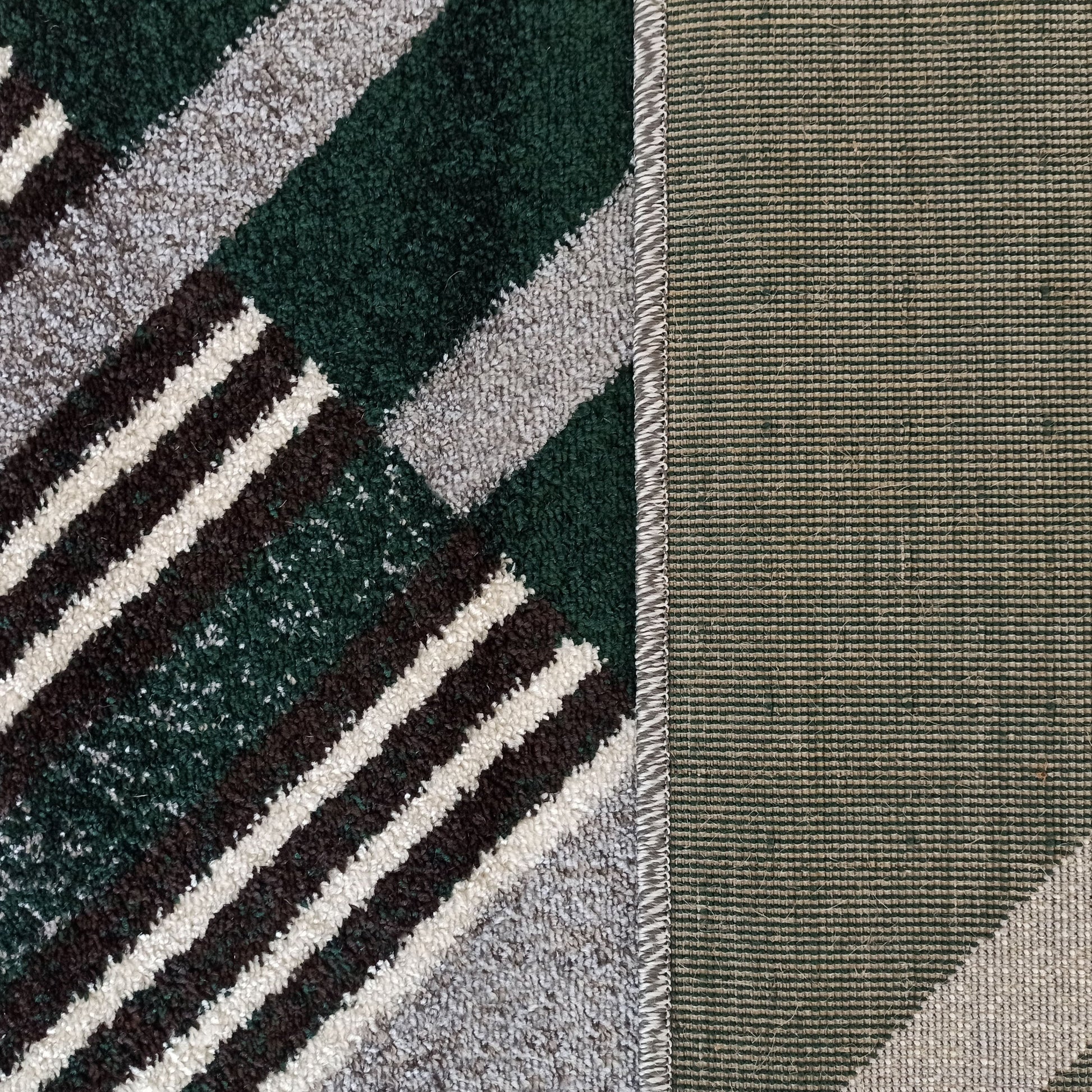Tapis épais à motif géométrique vert, gris, brun et blanc, avec une bordure tressée et un envers tissé strié vert et beige