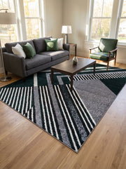 Tapis géométrique aux bandes asymétriques vert forêt, gris chiné, blanc et noir, sur un parquet clair d'un salon lumineux