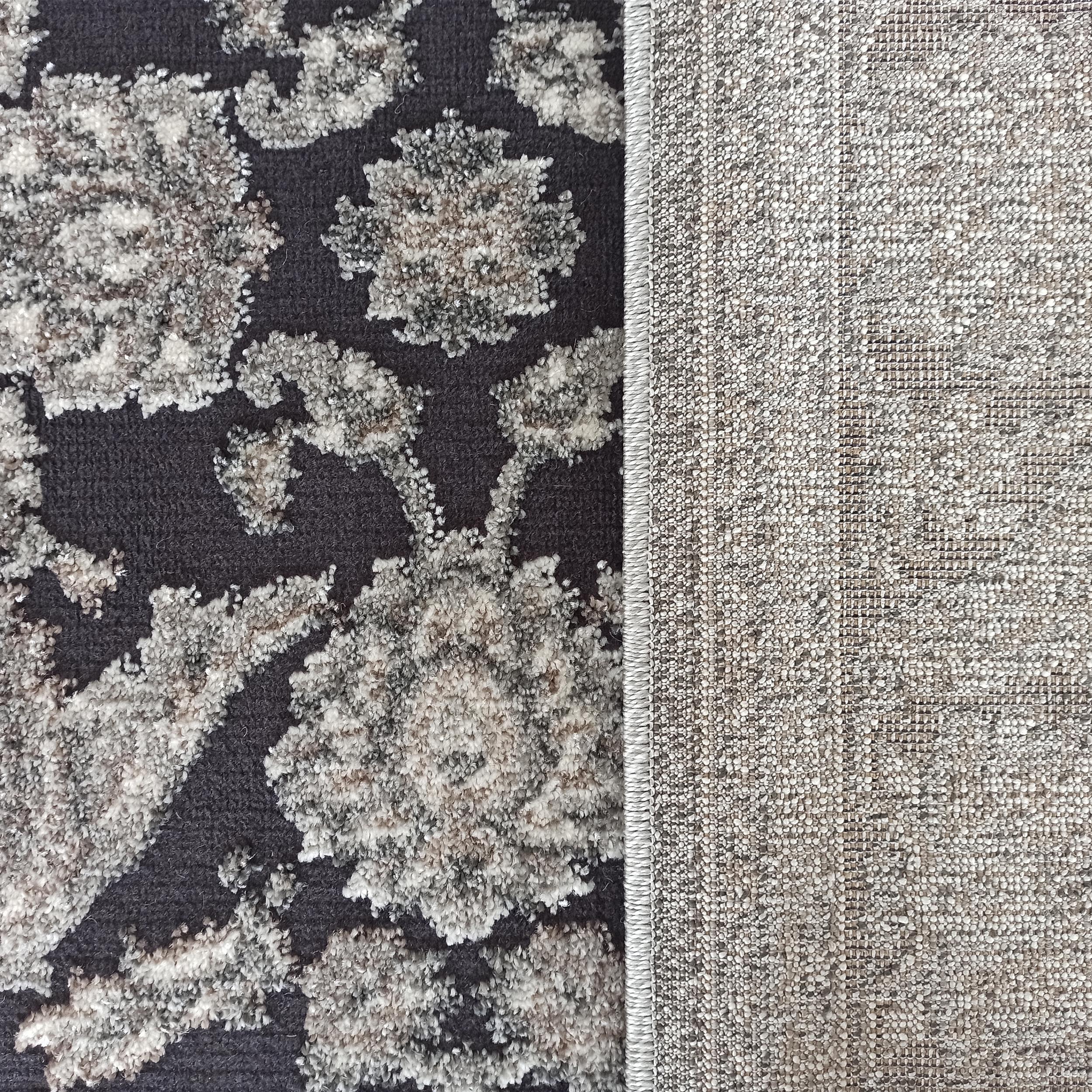 Tapis gris foncé avec des motifs floraux texturés gris clair et beige, et l'envers tissé en toile beige-gris