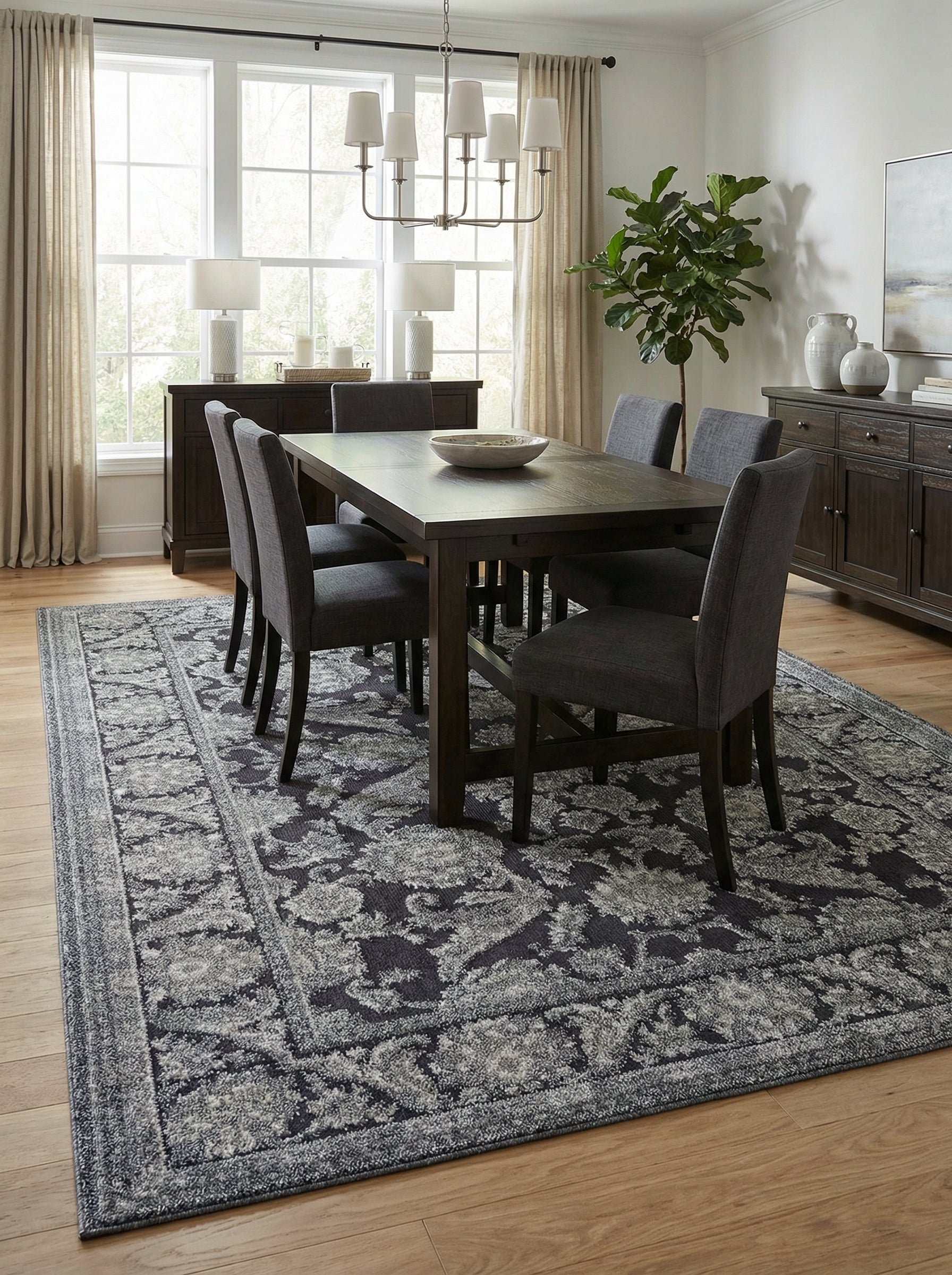 Tapis rectangulaire texturé gris anthracite aux motifs floraux et volutes gris clair effet vieilli, dans une salle à manger