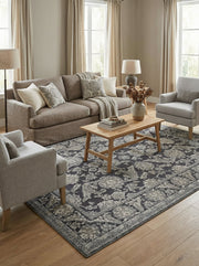 Tapis rectangulaire à fond gris anthracite et motifs floraux ornementaux gris clair texturés, dans un salon