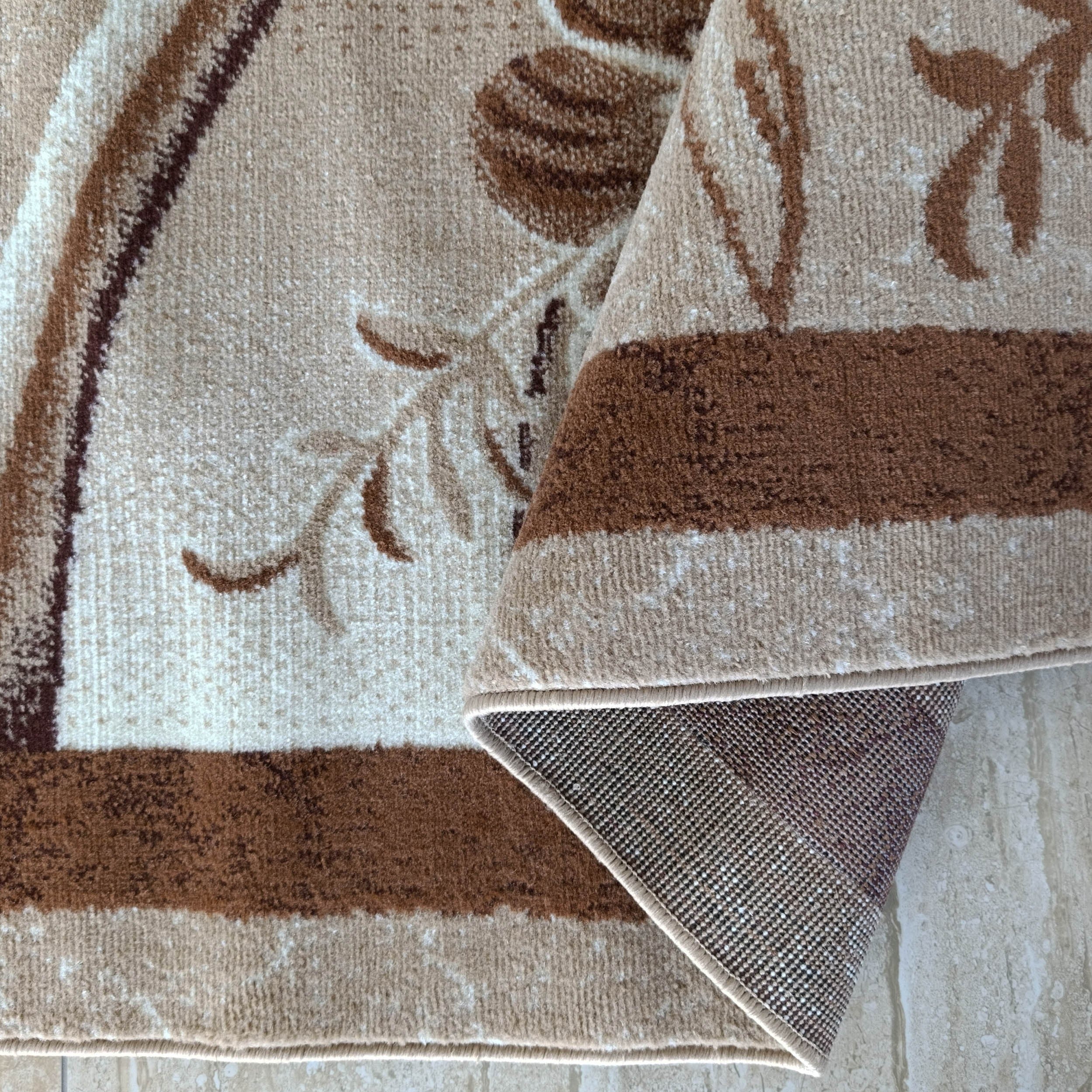 Un tapis beige et marron aux motifs floraux, partiellement replié, montrant son envers tissé et un sol clair