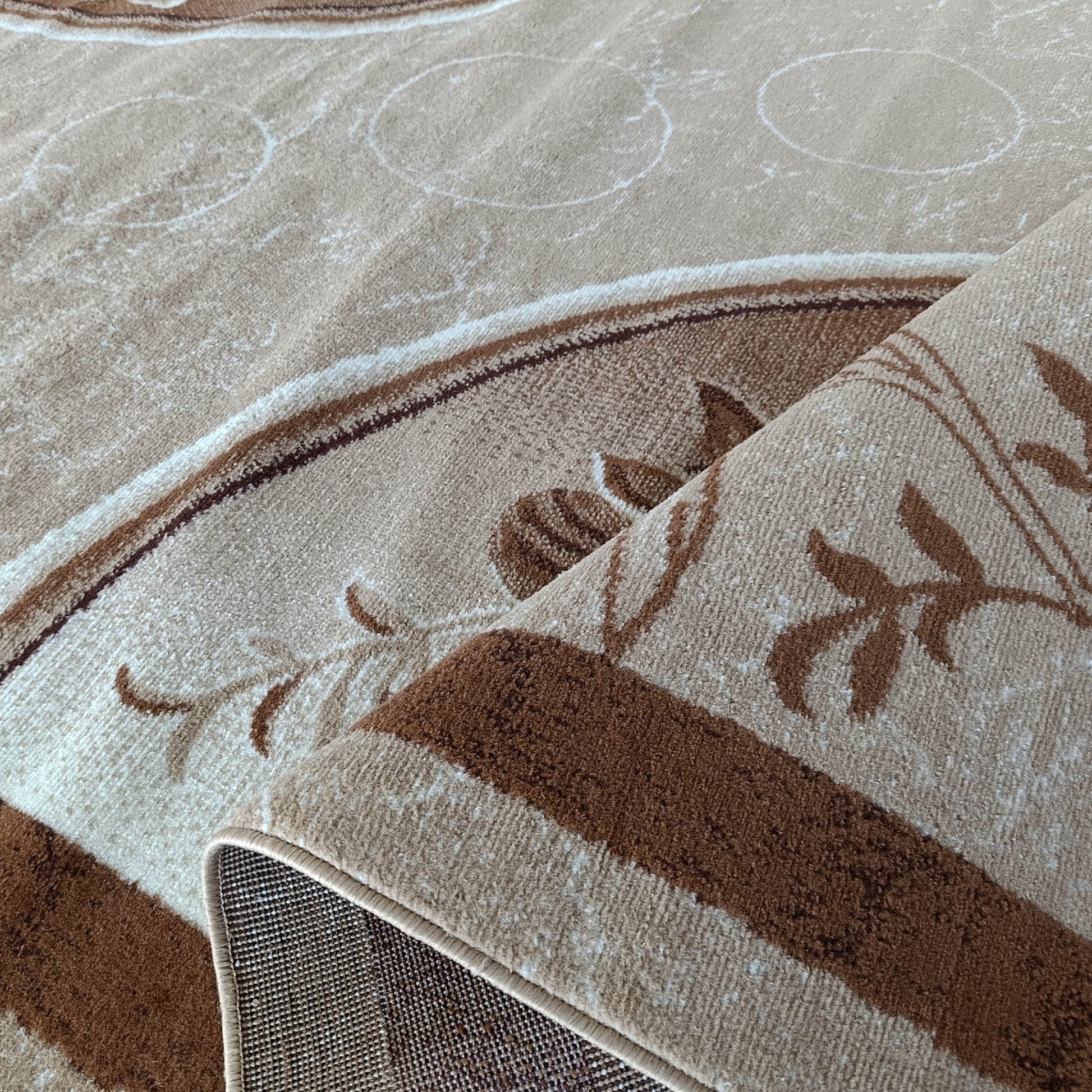 Tapis beige enroulé, révélant des motifs floraux marron, des bandes foncées et de discrets cercles sur sa surface visible