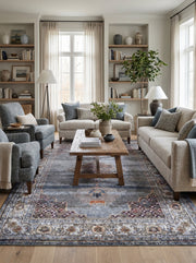 Tapis rectangulaire tissé aux motifs orientaux délavés de bleus profonds, gris, bordeaux et beige, dans un salon élégant