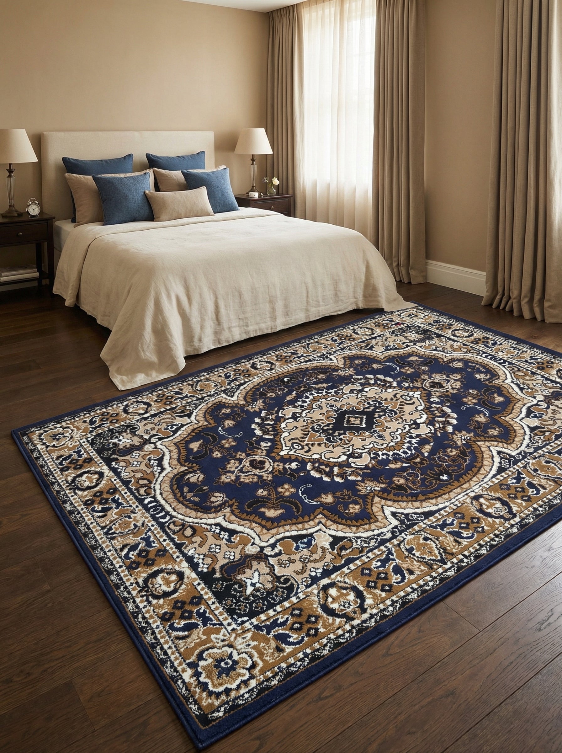 Tapis rectangulaire bleu marine à motifs orientaux beiges, marron et crème, posé sur un parquet en bois foncé dans une chambre