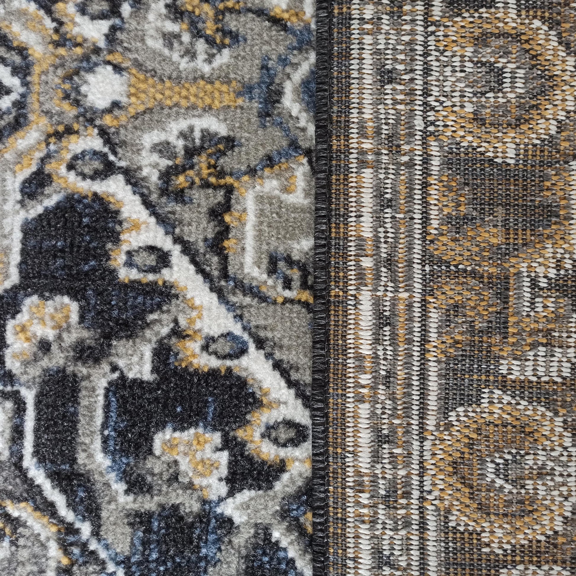 Tapis en gros plan, combinant un velours ornemental gris, noir, blanc, jaune et bleu avec un tissage plat texturé multicolore