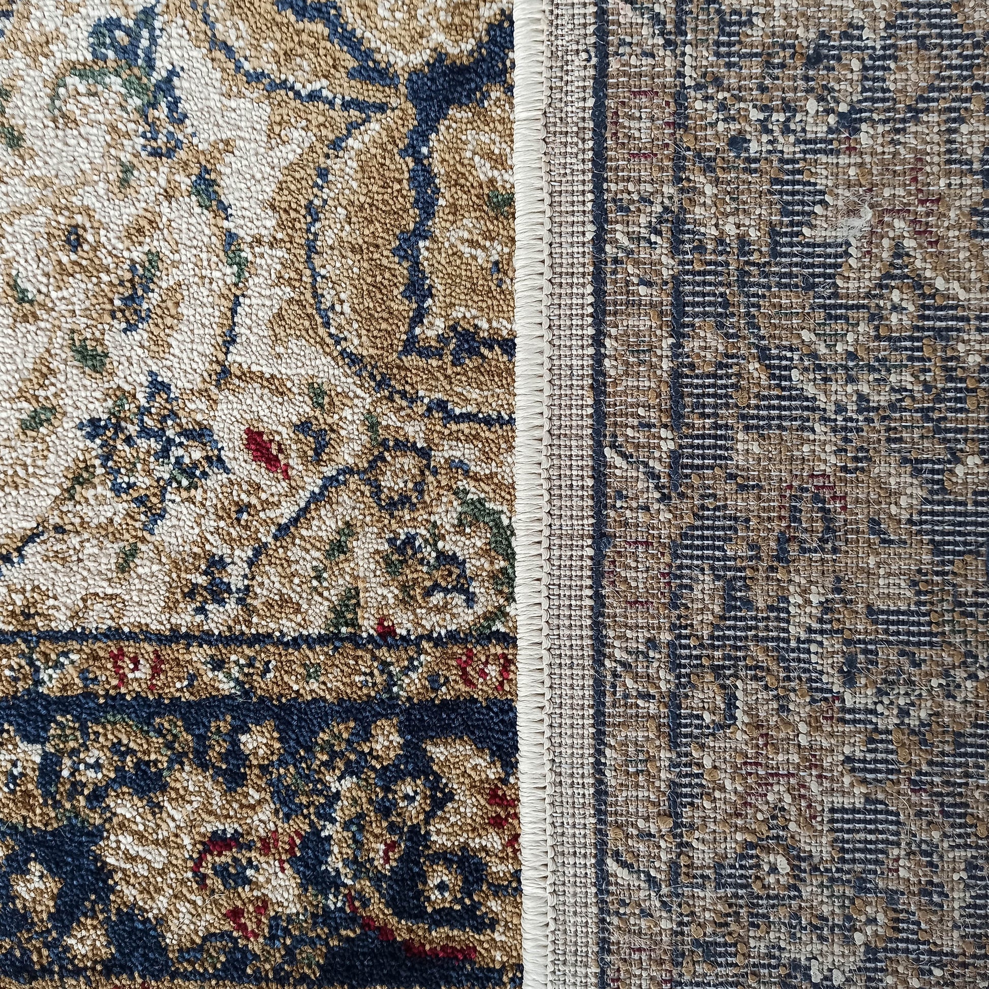 Gros plan sur un tapis avec un motif floral beige et bleu marine en velours bouclé et son envers tissé