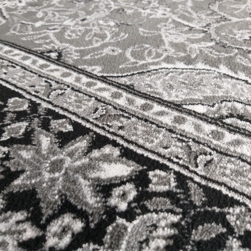 Tapis textile à motifs traditionnels noirs, gris et blancs avec des bandes décoratives et des dessins floraux