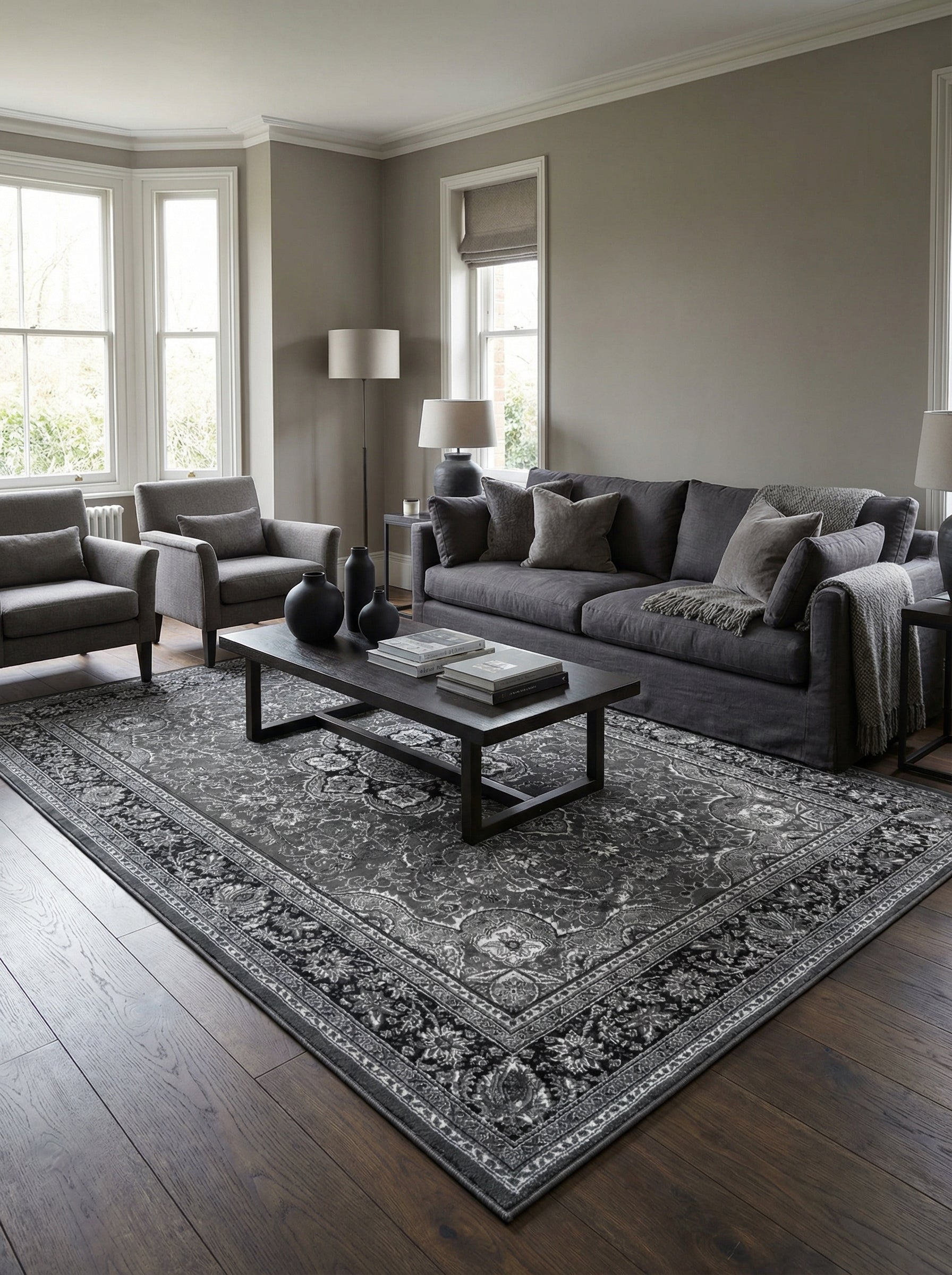 Tapis rectangulaire gris foncé et noir aux motifs floraux et cachemire complexes, posé sur un parquet sombre dans un salon élégant