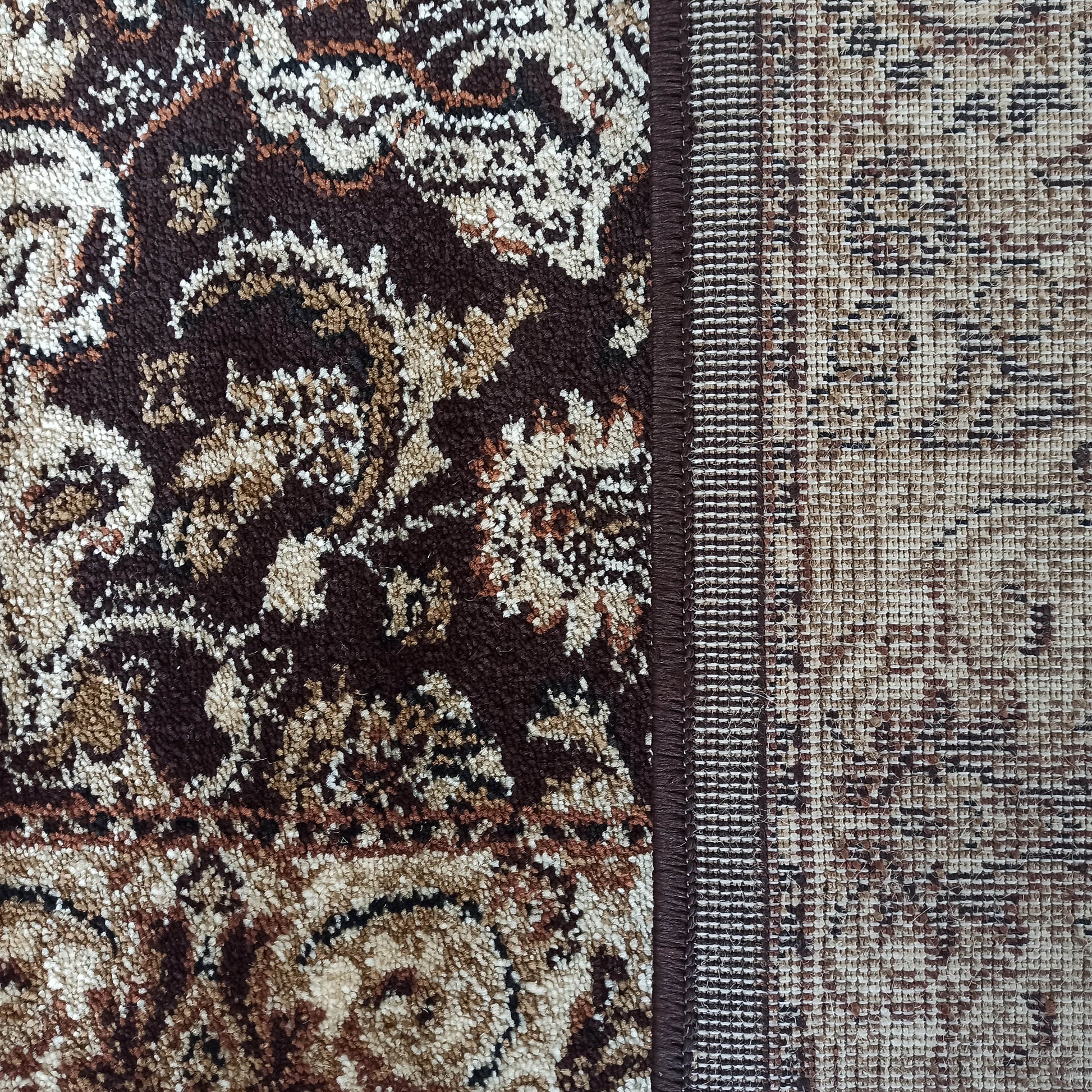 Tapis présentant une surface touffue marron foncé et beige à motifs ornementaux, adjacente à une section tissée plus claire