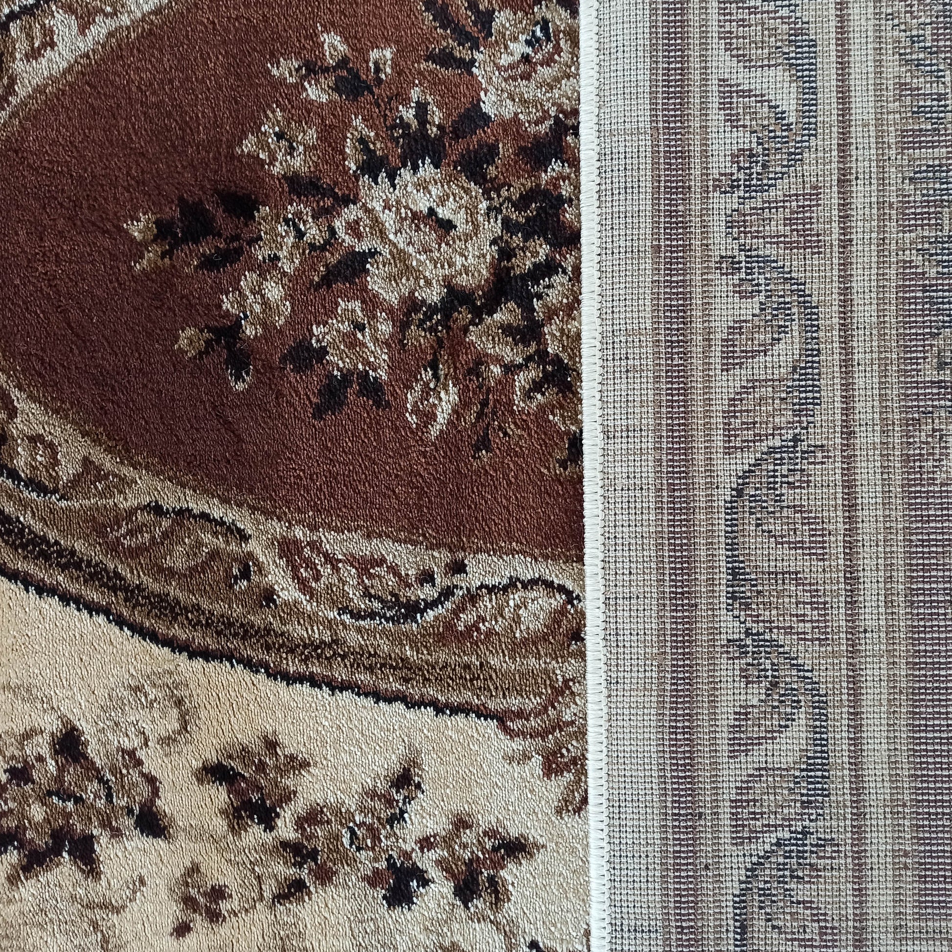 Tapis marron et beige présentant sur la gauche un côté doux à motifs floraux et sur la droite son envers tissé à rayures
