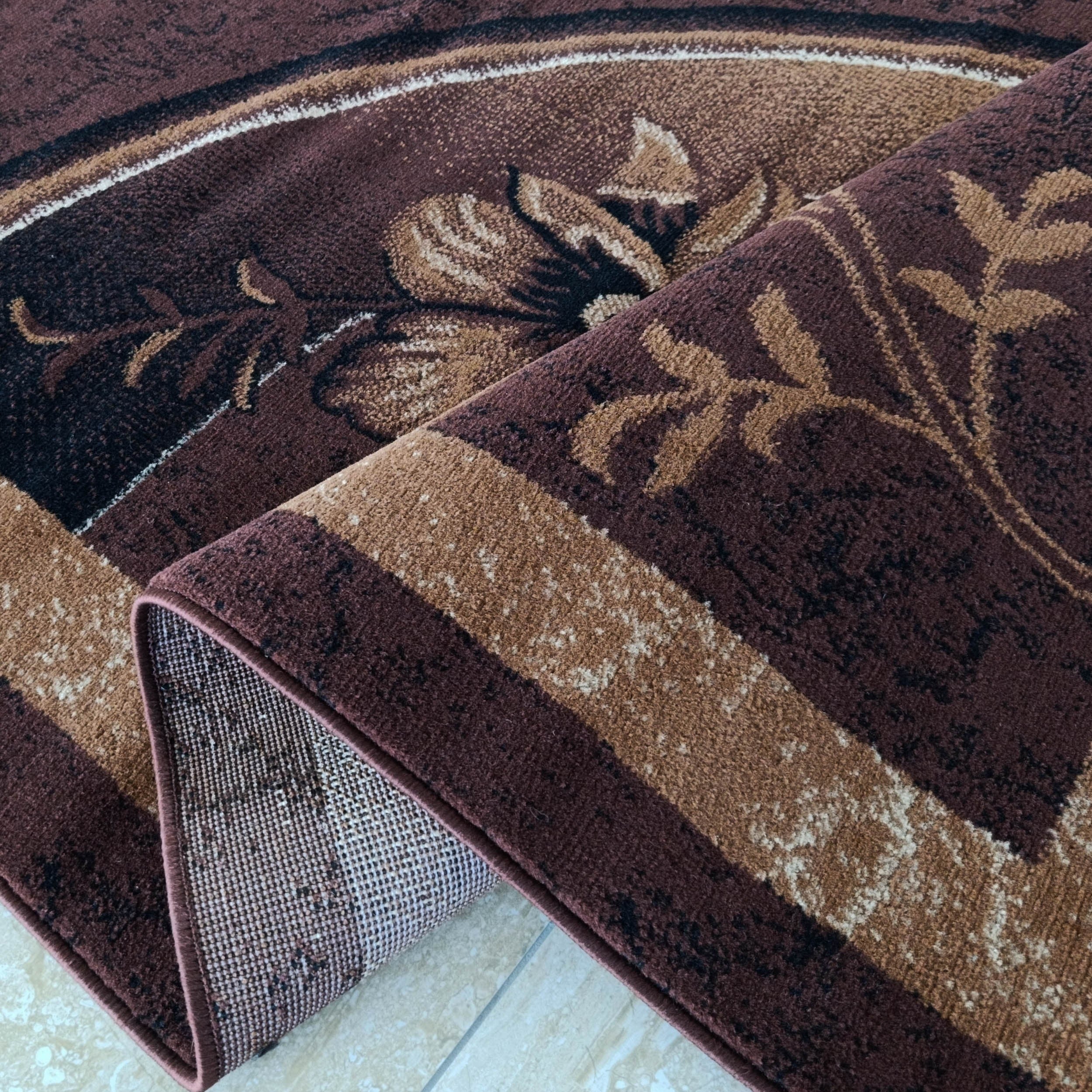 Tapis marron foncé à motifs floraux beiges et crème, envers tissé, bords cousus, partiellement roulé sur carrelage clair