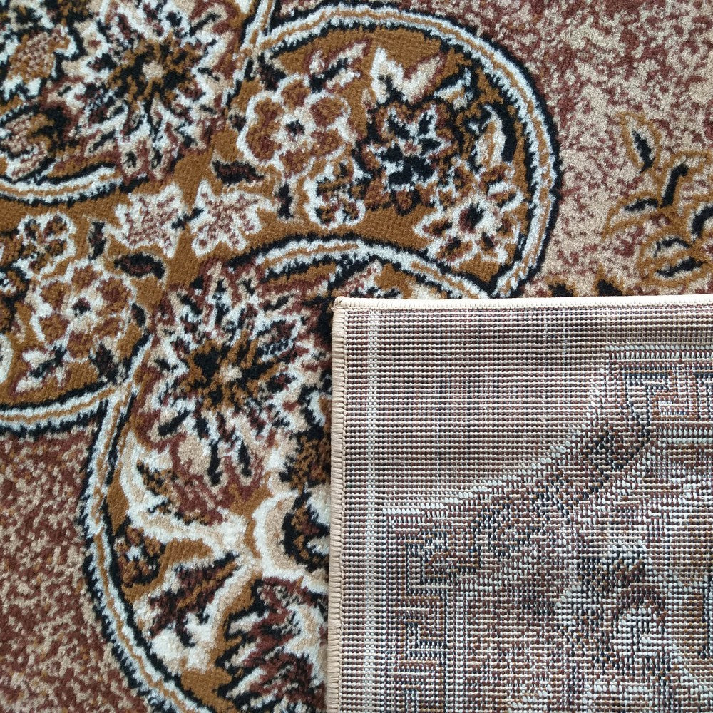 Tapis aux motifs floraux et paisley dans des tons de marron, noir et blanc cassé, avec un coin relevé montrant l'envers tissé