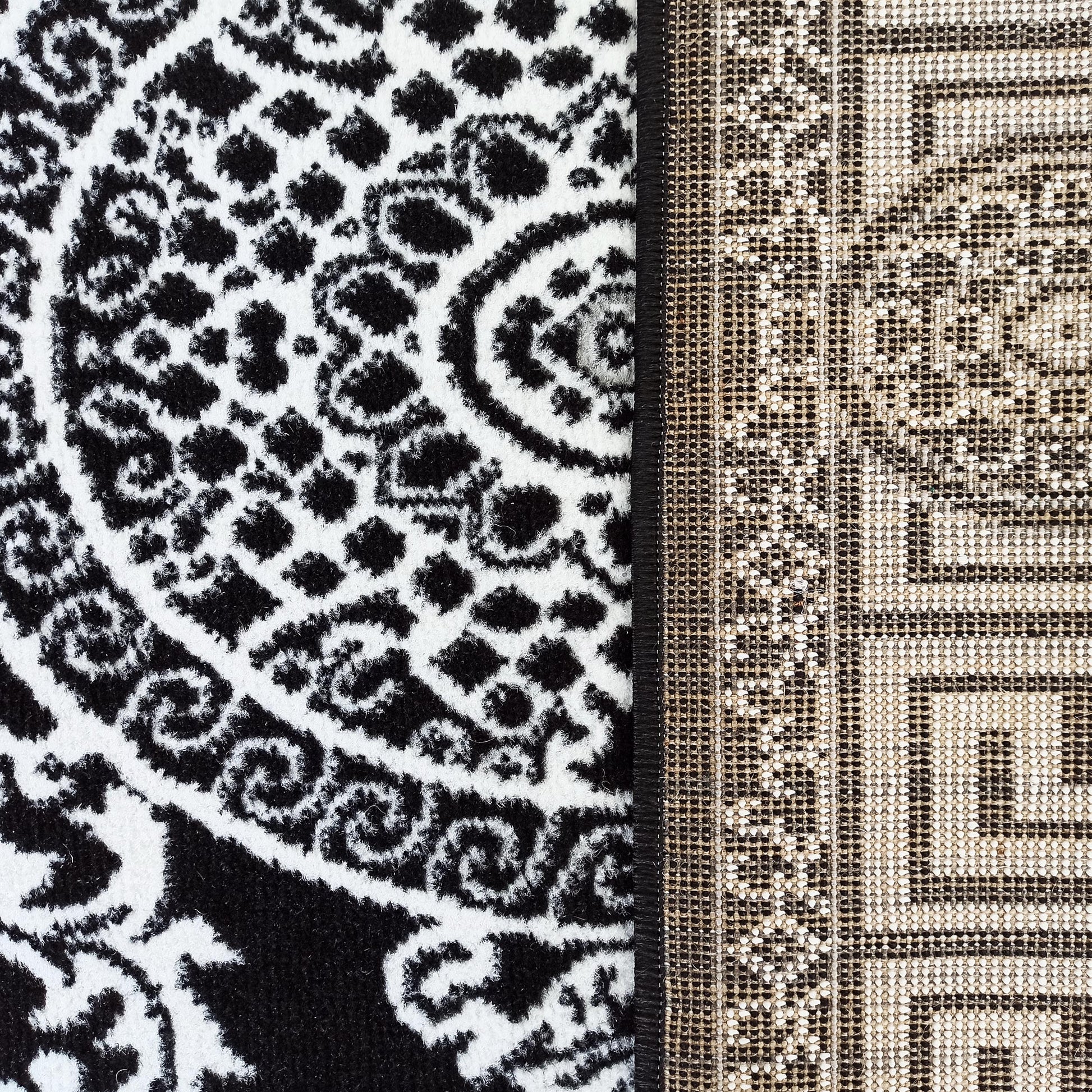 Tapis bicolore avec un motif floral abstrait noir et blanc sur la surface et un tissage beige-noir visible sur l'envers