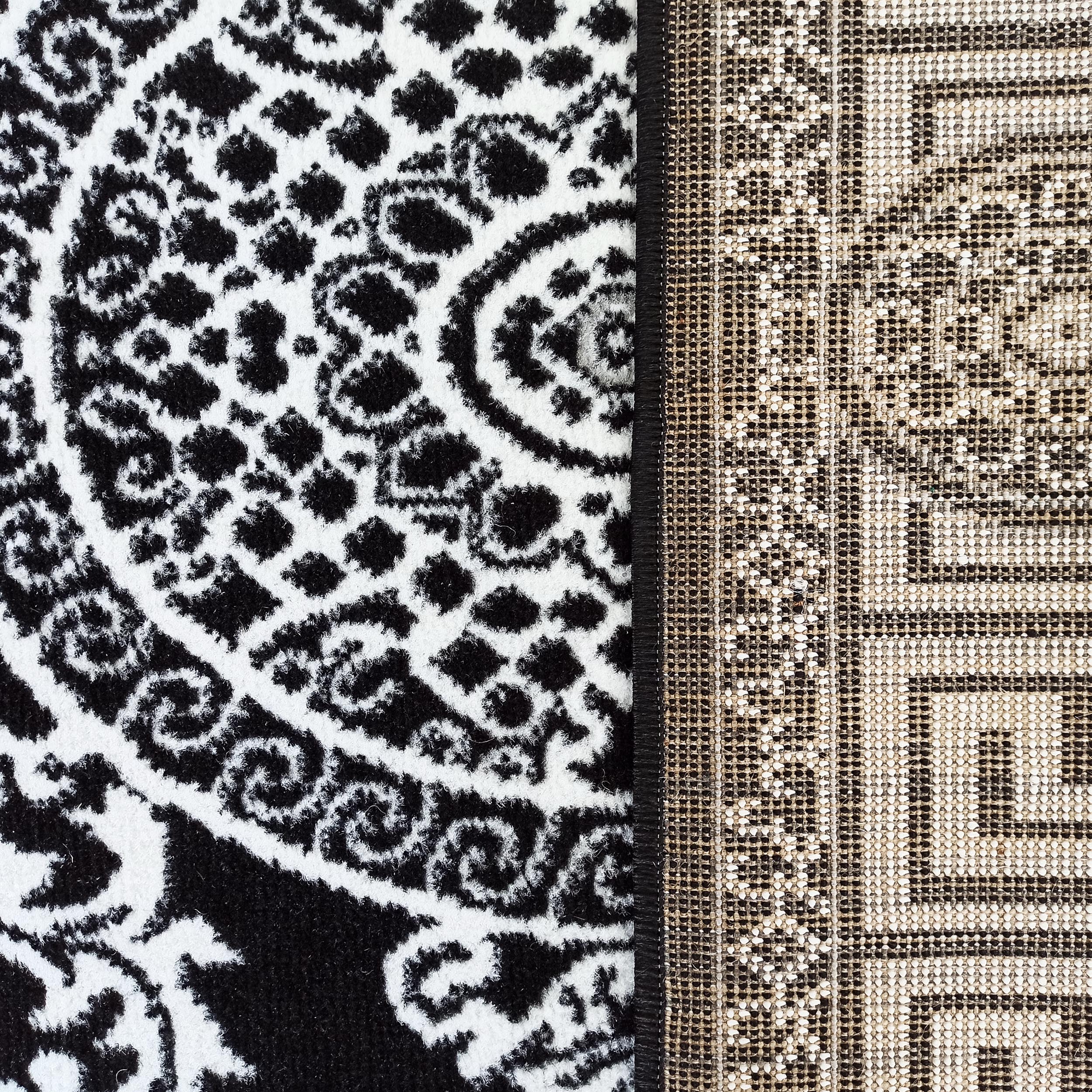 Tapis bicolore avec un motif floral abstrait noir et blanc sur la surface et un tissage beige-noir visible sur l'envers
