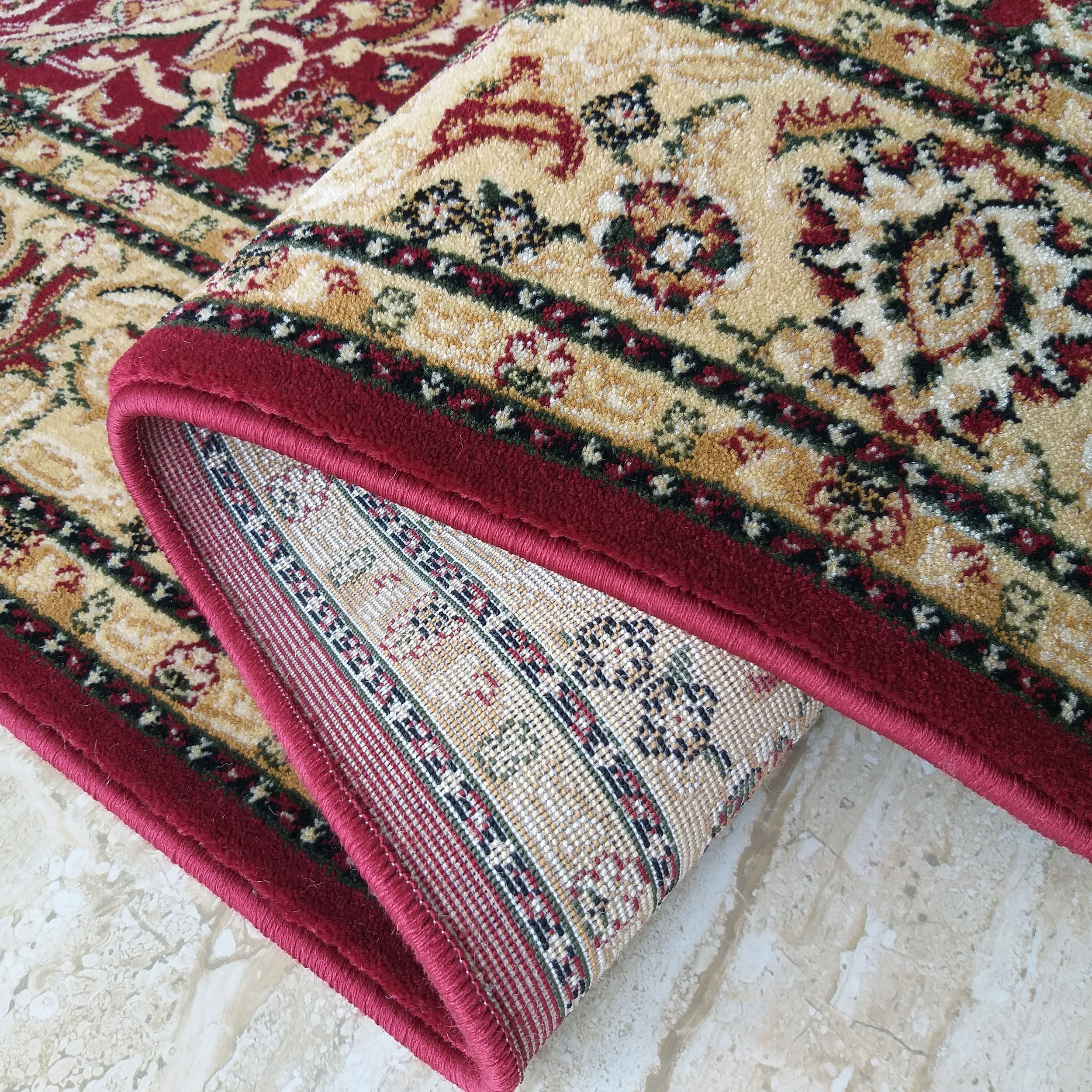 Tapis roulé à motifs ornementaux traditionnels rouges, beiges, verts et dorés sur fond crème, avec une bordure rouge vif et l'envers tissé exposé