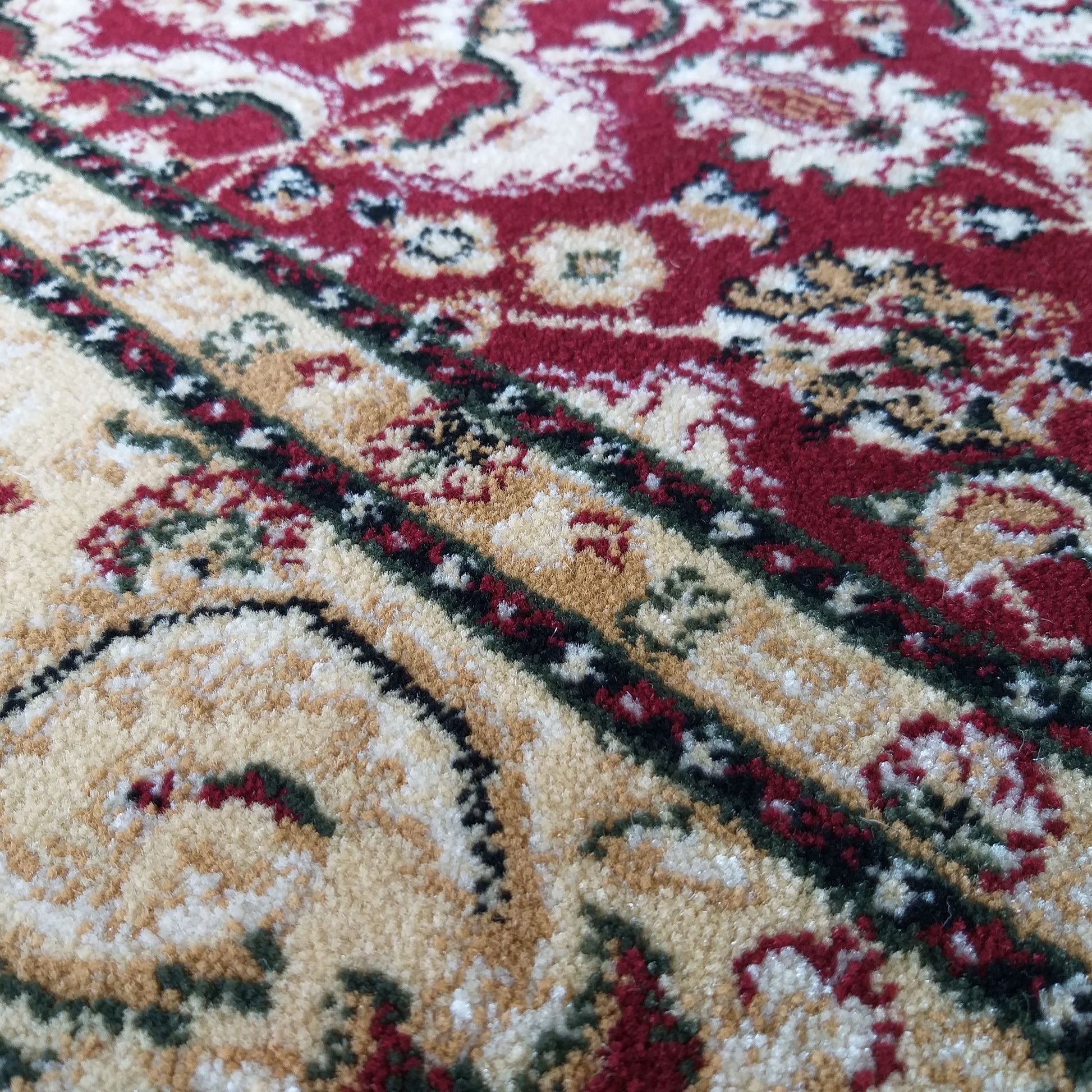 Tapis aux motifs orientaux rouges et beiges, ornés de détails verts et noirs sur une texture douce et veloutée