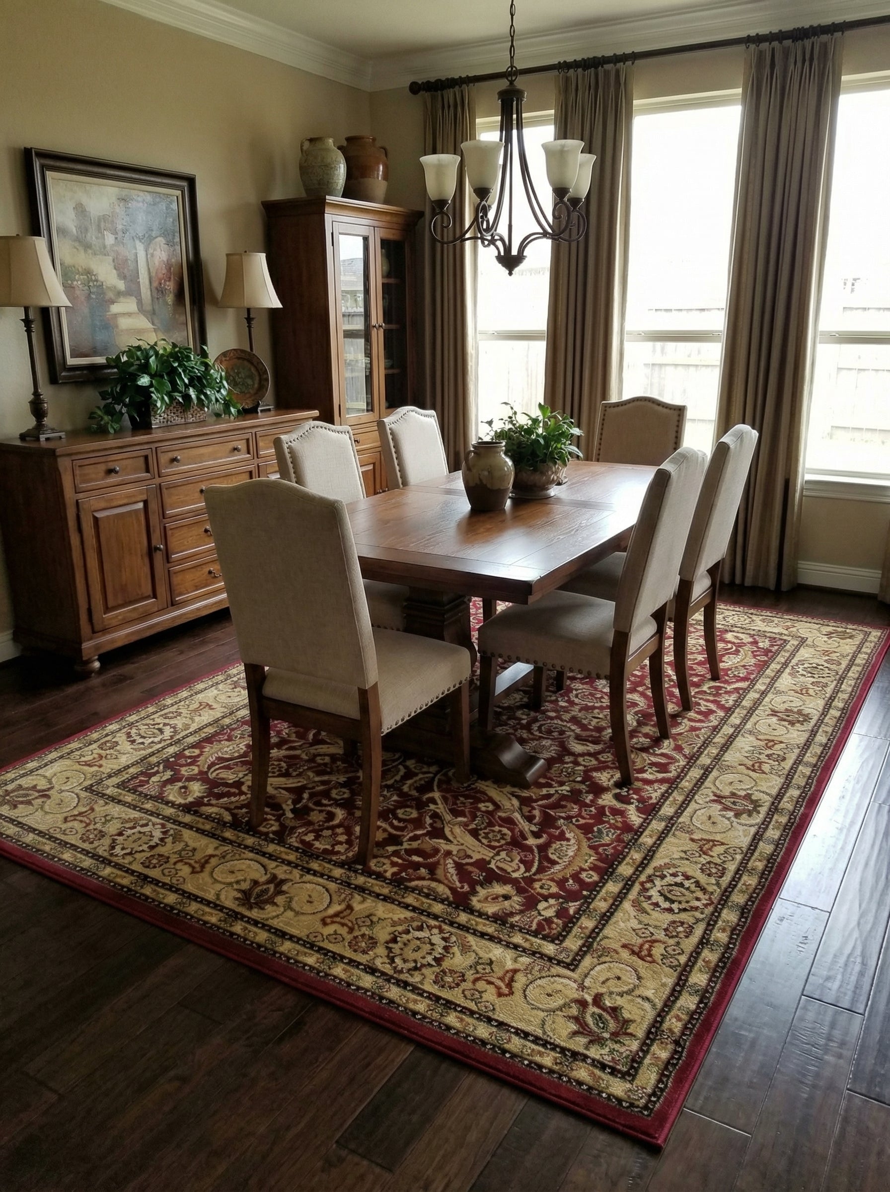 Tapis rectangulaire à motifs persans rouge bordeaux, crème et or avec bordure complexe, sous une table de salle à manger en bois