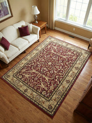 Tapis rectangulaire bordeaux et beige à motifs floraux traditionnels, posé sur un parquet clair dans un salon