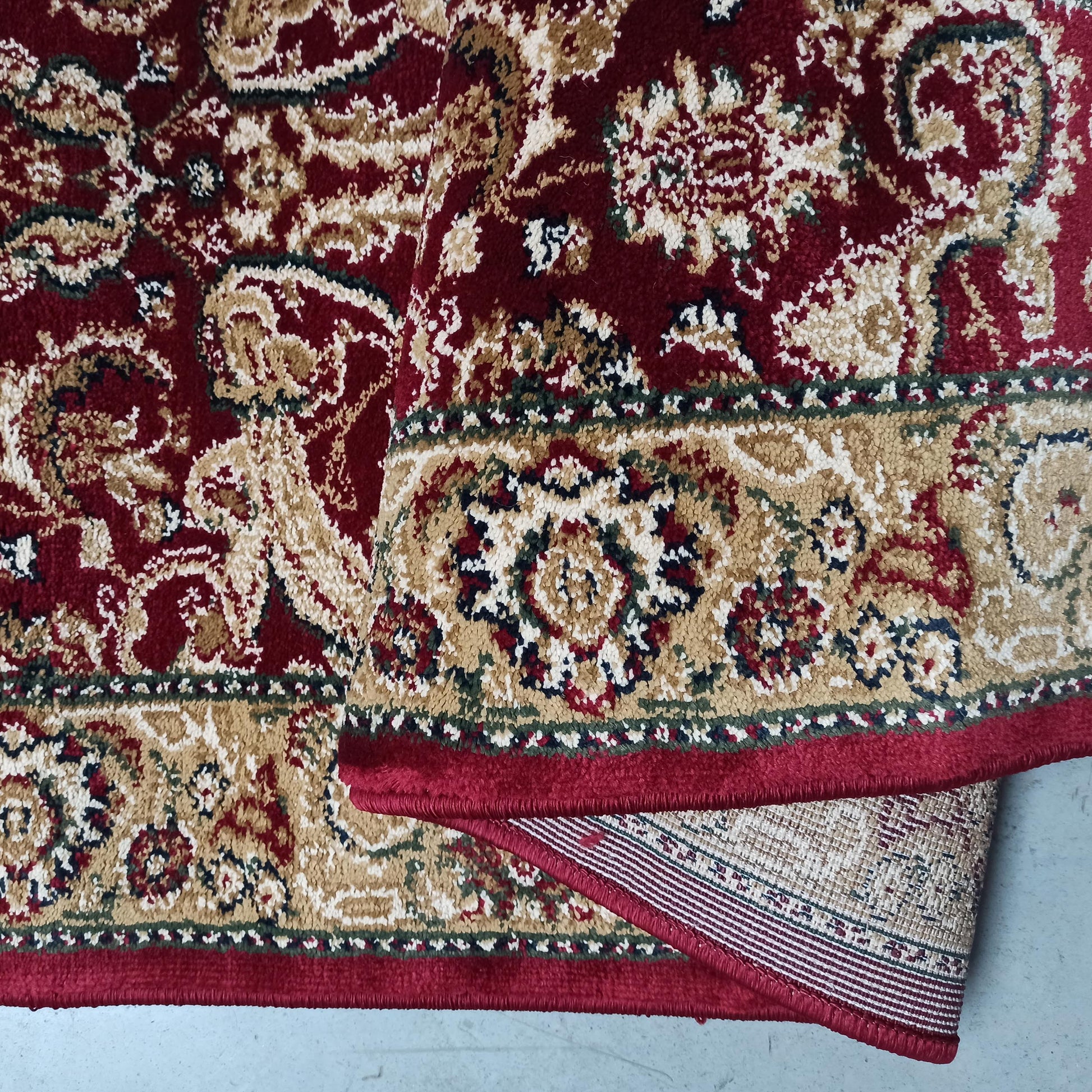 Tapis en velours bouclé rouge bordeaux et orné de motifs floraux dorés, crèmes et verts