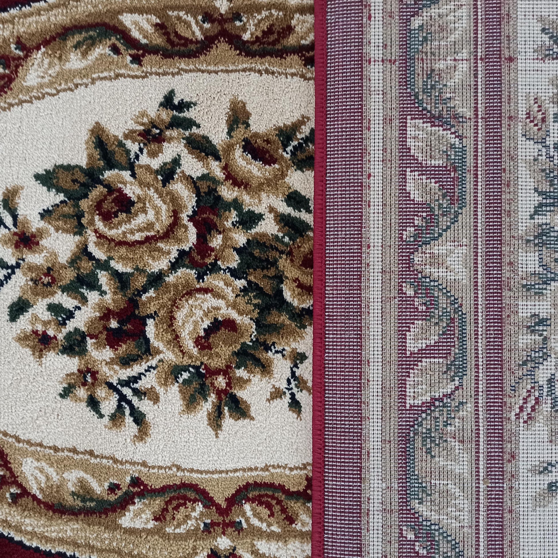 Tapis au velours floral crème, doré et rouge avec des feuilles vertes, côtoyant une section tissée à rayures rouges et beiges, séparée par un liseré bordeaux