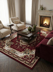Tapis rectangulaire rouge bordeaux à motifs floraux et volutes crème et or dans un salon chaleureux