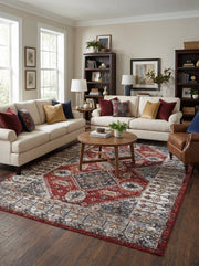 Tapis rectangulaire à motifs persans vieillis, rouge, bleu marine, beige et gris crème, au centre d'un salon