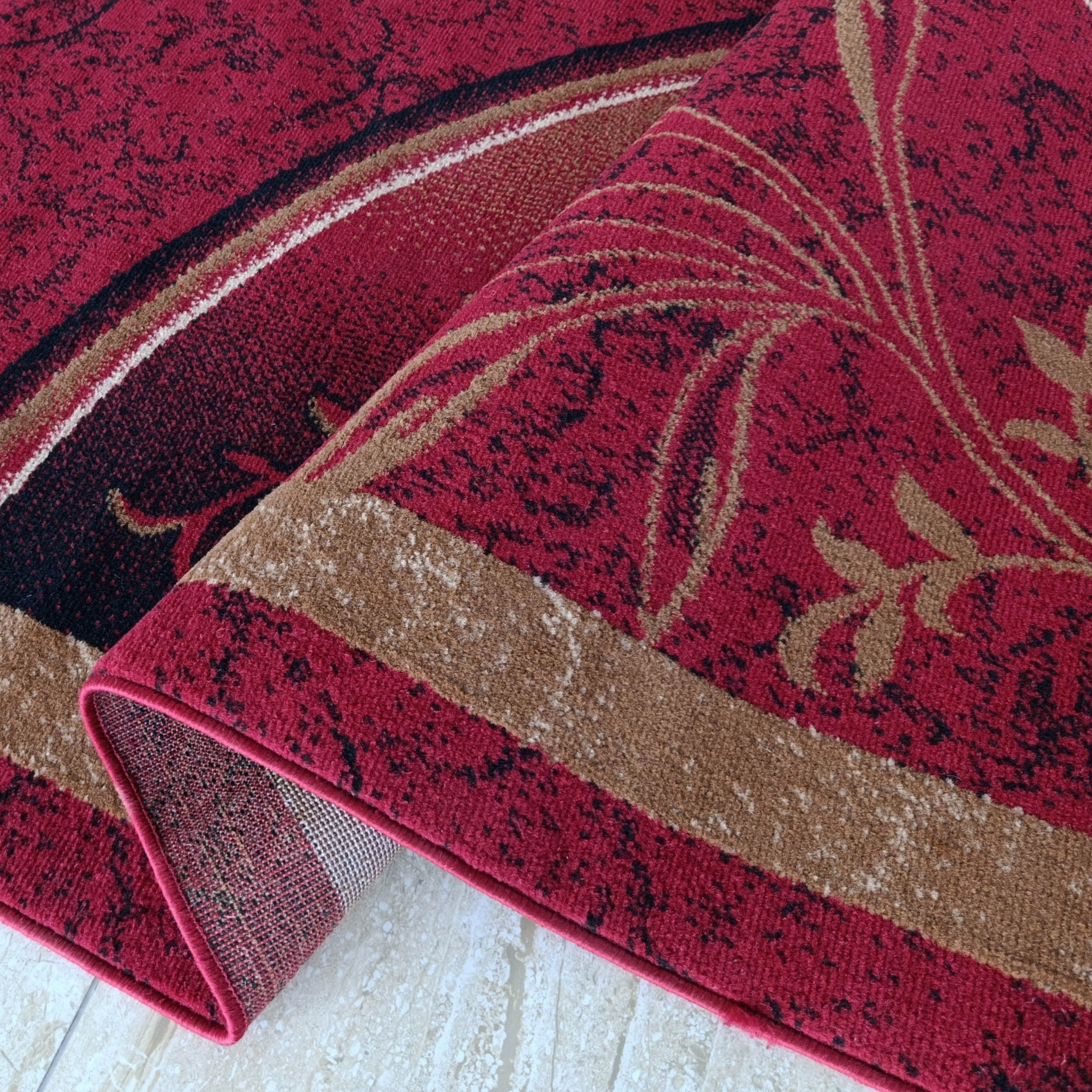 Tapis rouge bordeaux avec motifs floraux beiges et taches noires, partiellement roulé sur un sol clair
