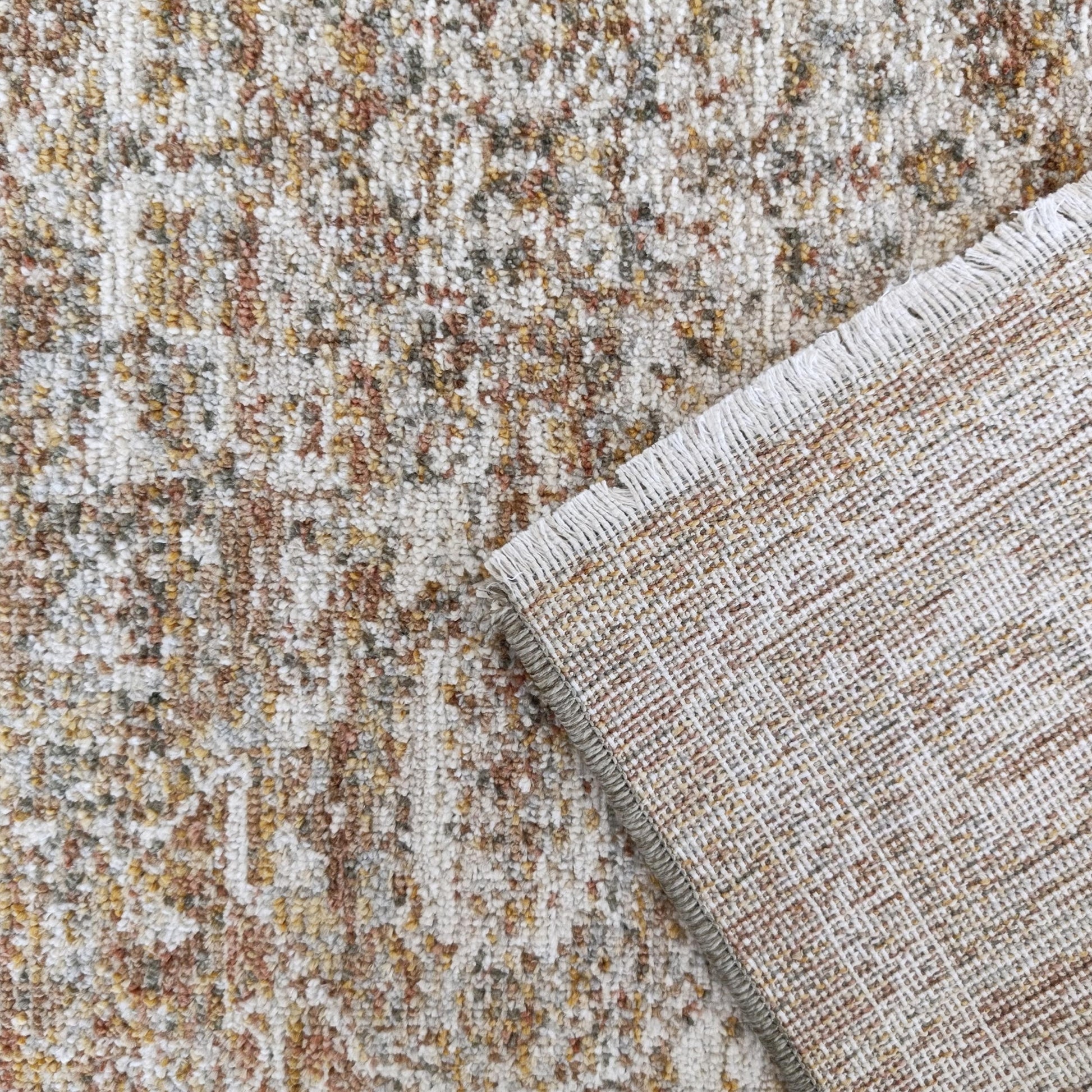 Tapis texturé aux motifs mouchetés crème, marron et ocre, avec son envers tissé aux motifs quadrillés apparents