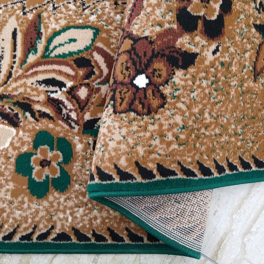 Tapis floral beige à motifs marron et noirs de fleurs et feuilles vertes, avec bordure vert foncé, plié pour révéler son envers tissé