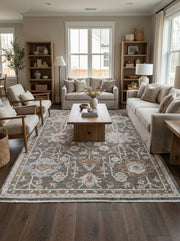 Tapis rectangulaire gris foncé aux motifs floraux et médaillons complexes blanc cassé, rouille et beige, posé dans un salon