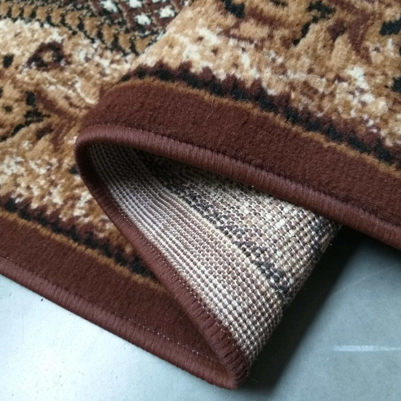 Tapis à la surface douce, aux motifs beiges et marron foncé, bordé de brun et montrant son envers tissé