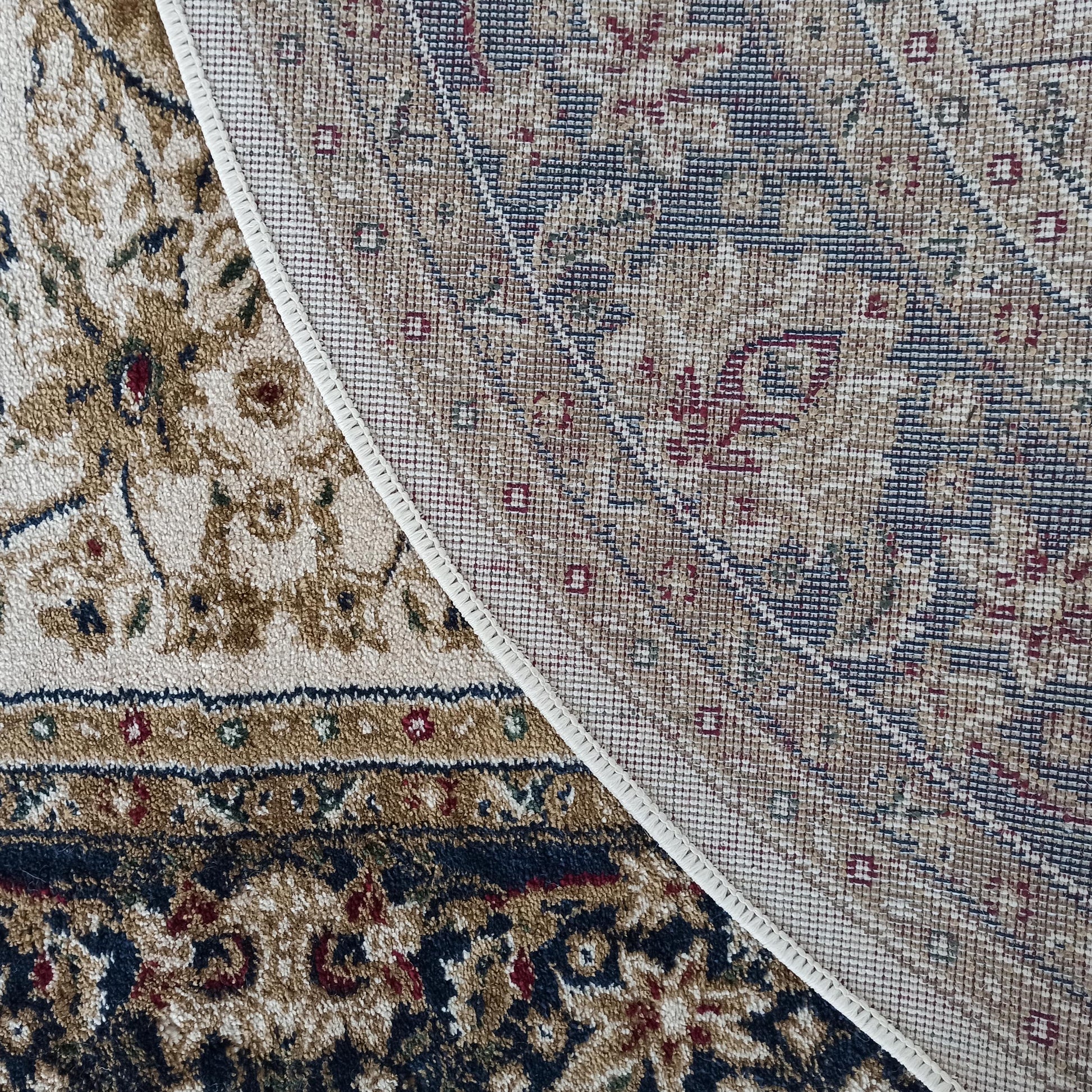Tapis velouté aux motifs ornementaux beiges, marrons, bleus et rouges, partiellement replié sur son dos tissé