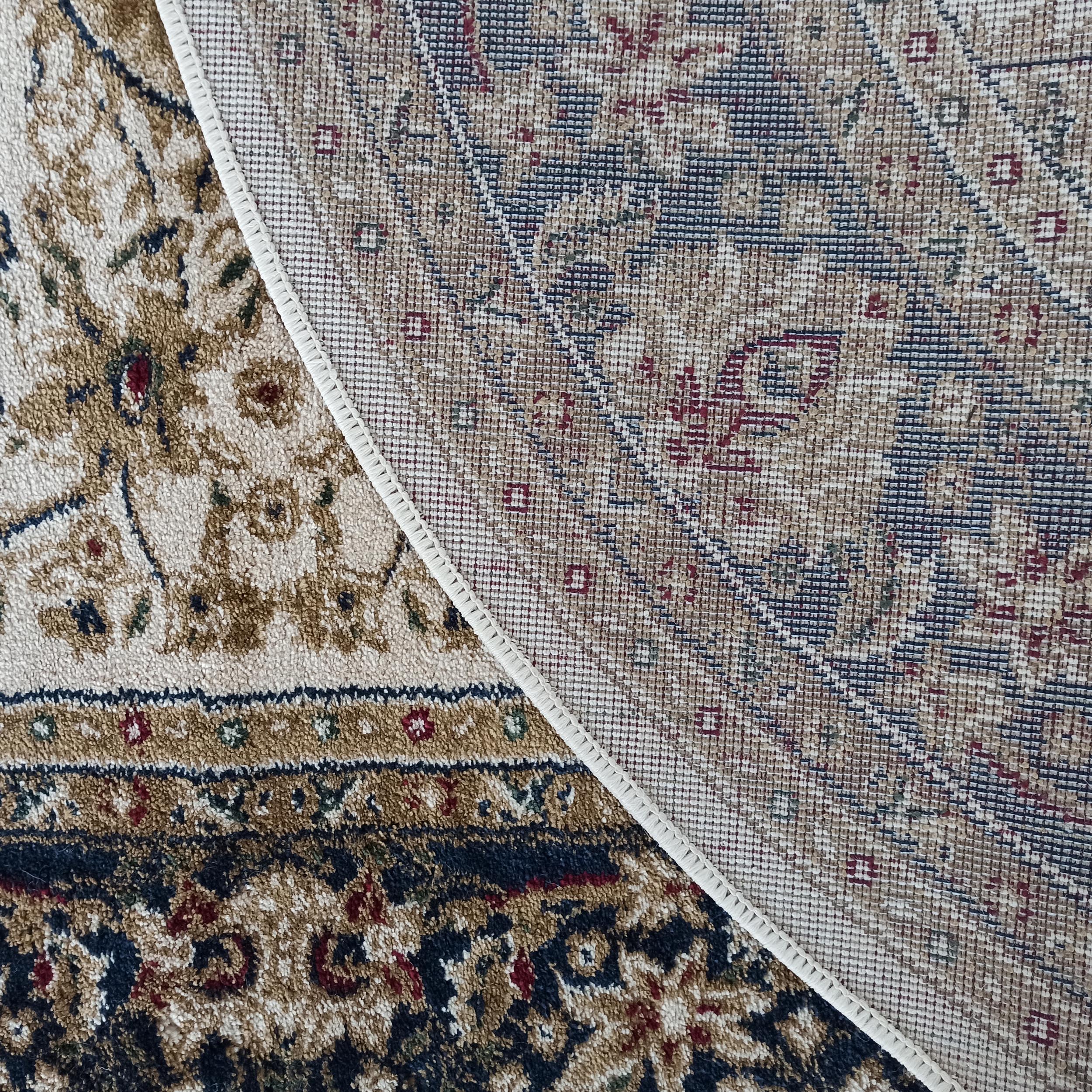 Tapis velouté aux motifs ornementaux beiges, marrons, bleus et rouges, partiellement replié sur son dos tissé