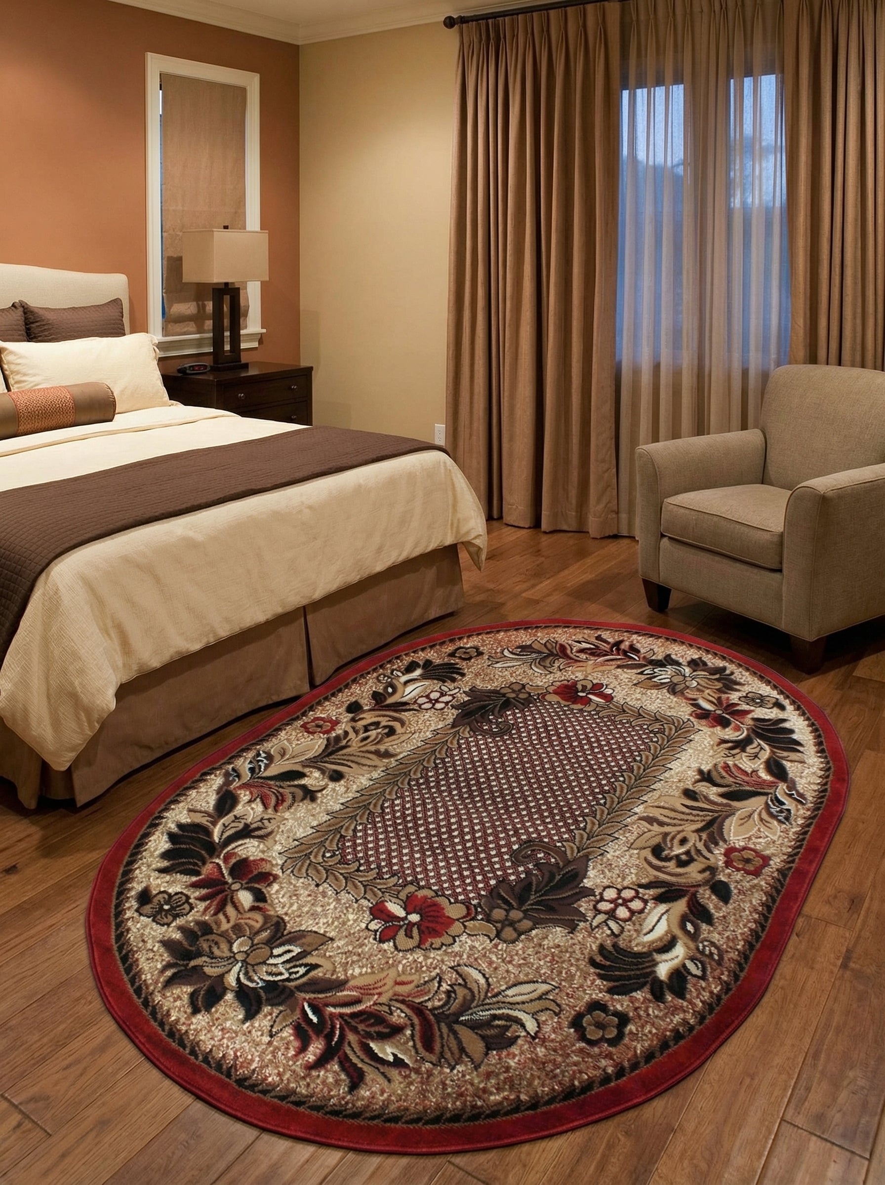 Tapis ovale beige orné de grands motifs floraux rouges, marrons et noirs, avec une bordure rouge vif, dans une chambre au parquet clair